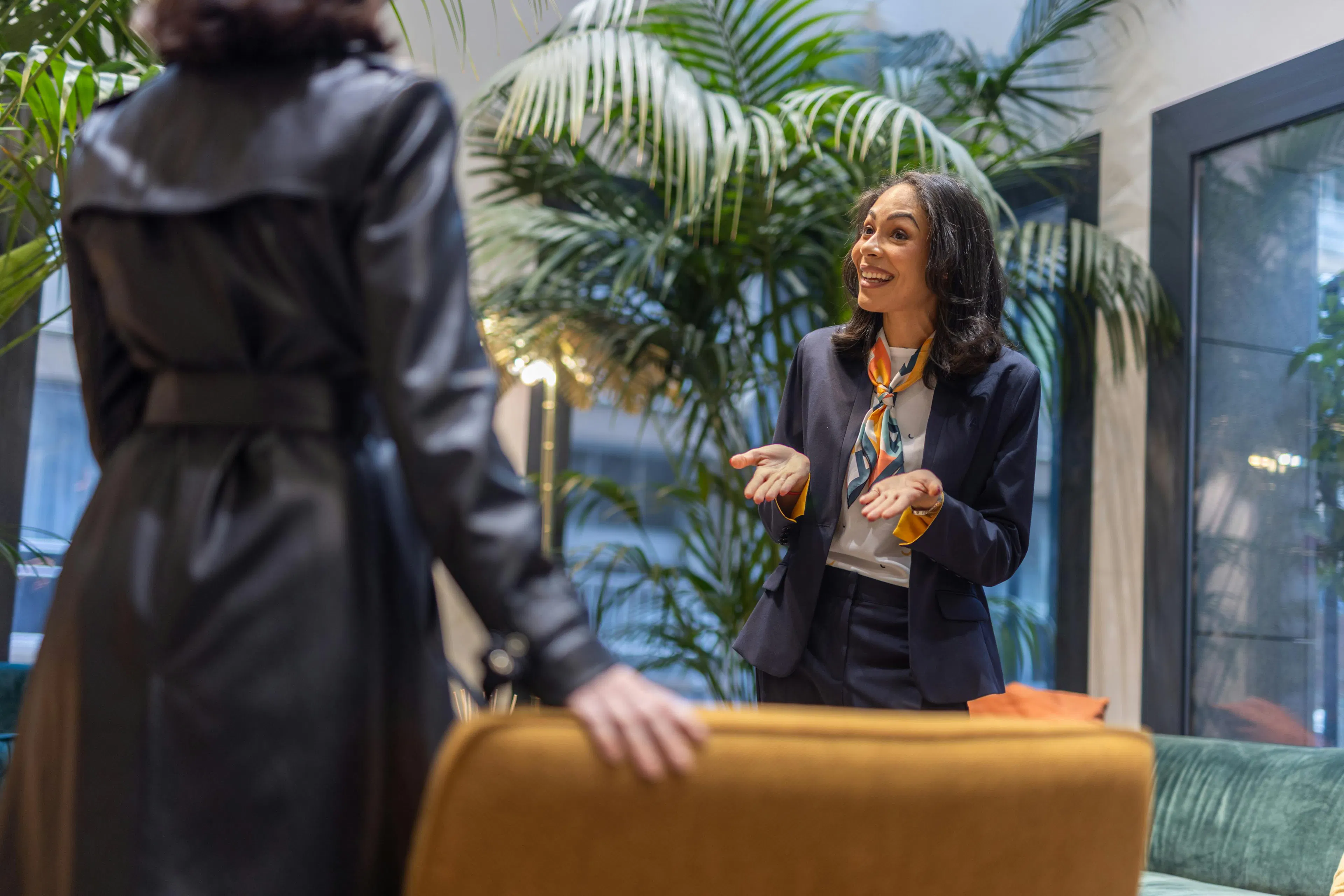 A receptionist at the reception desk of a company welcoming a visitor