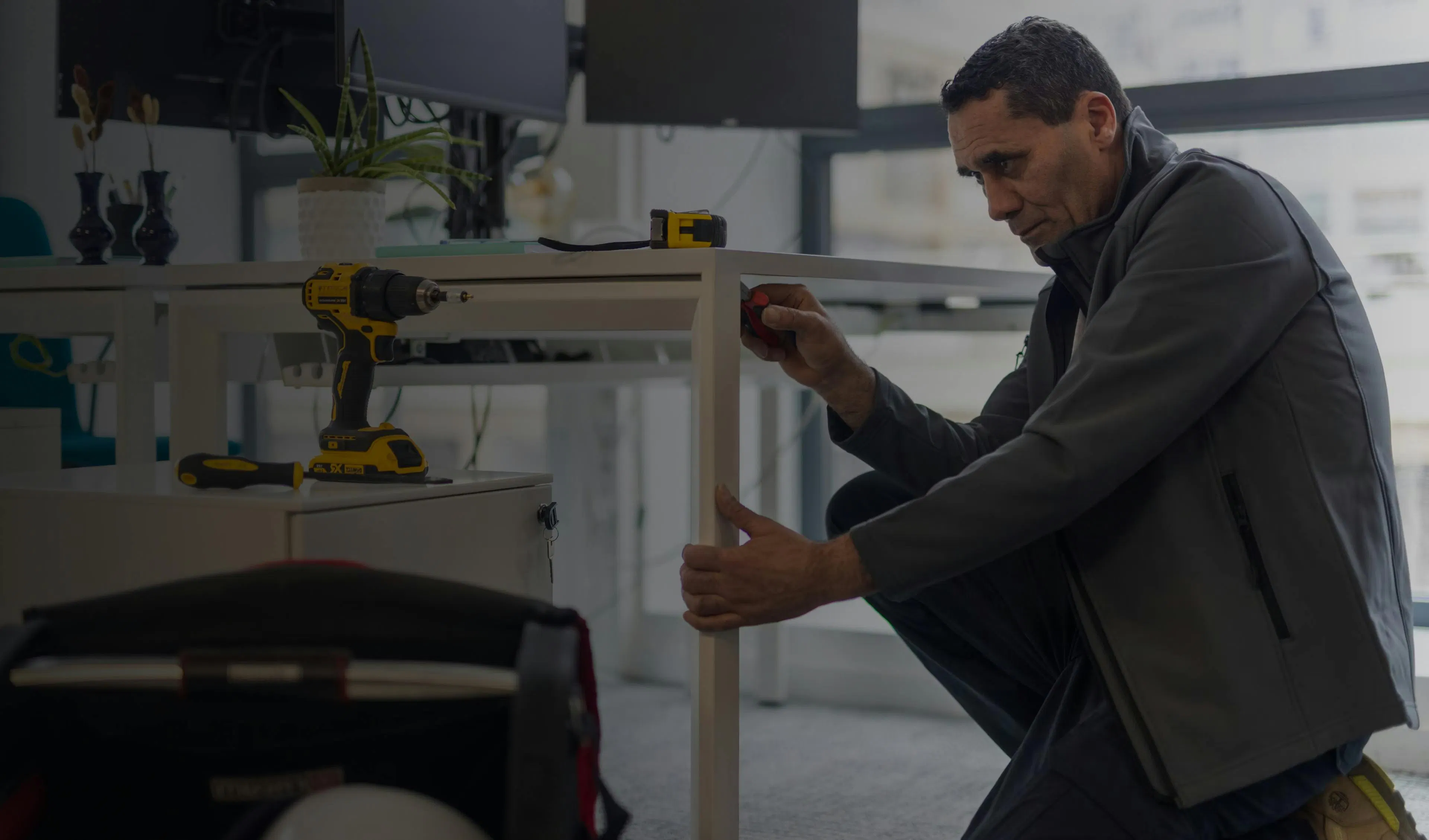 A maintenance agent repairing a desk
