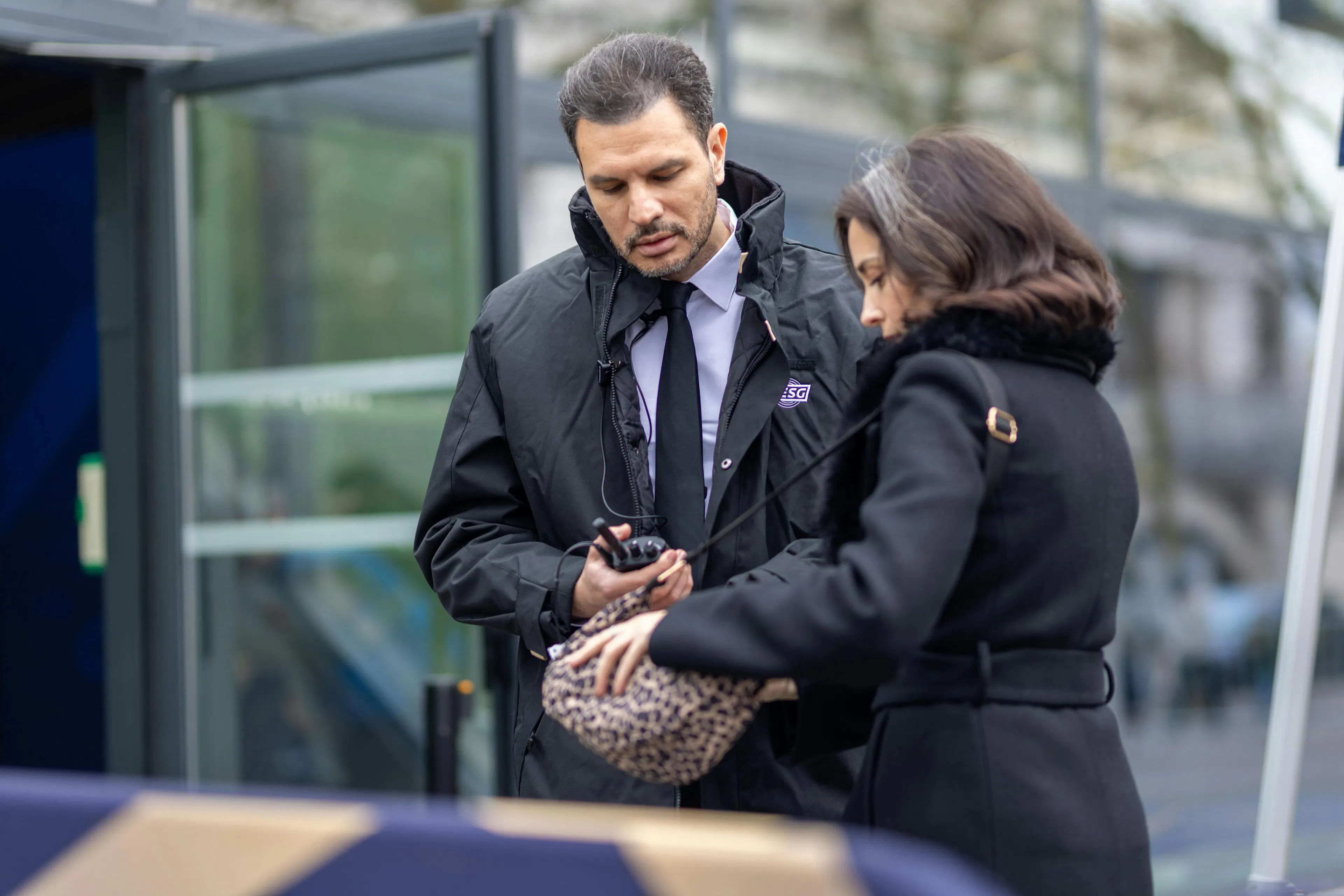 A security guard screening a visitor at the entrance of an event site