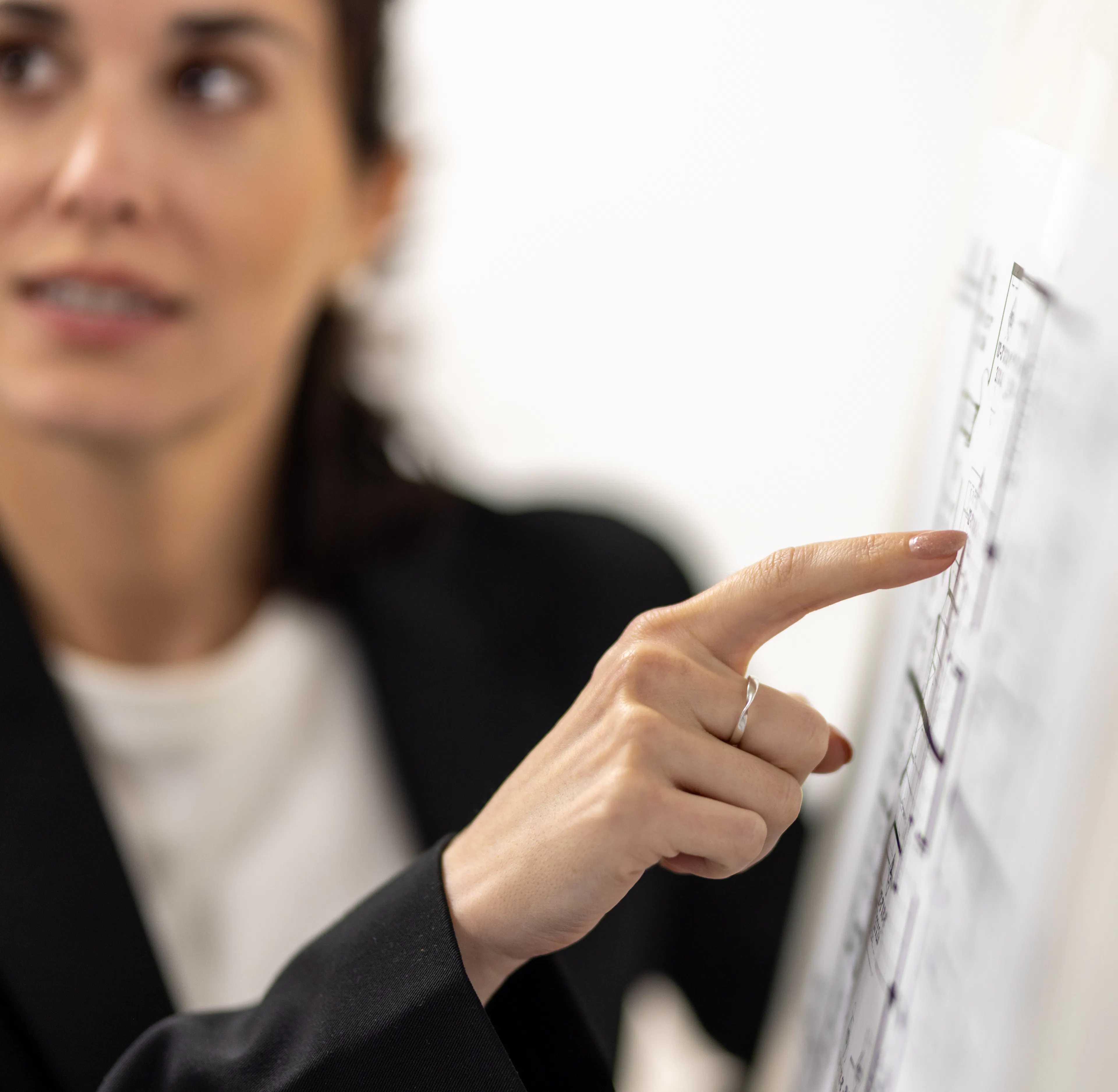 Une collaboratrice montrant un élément spécifique sur un plan d'immeuble