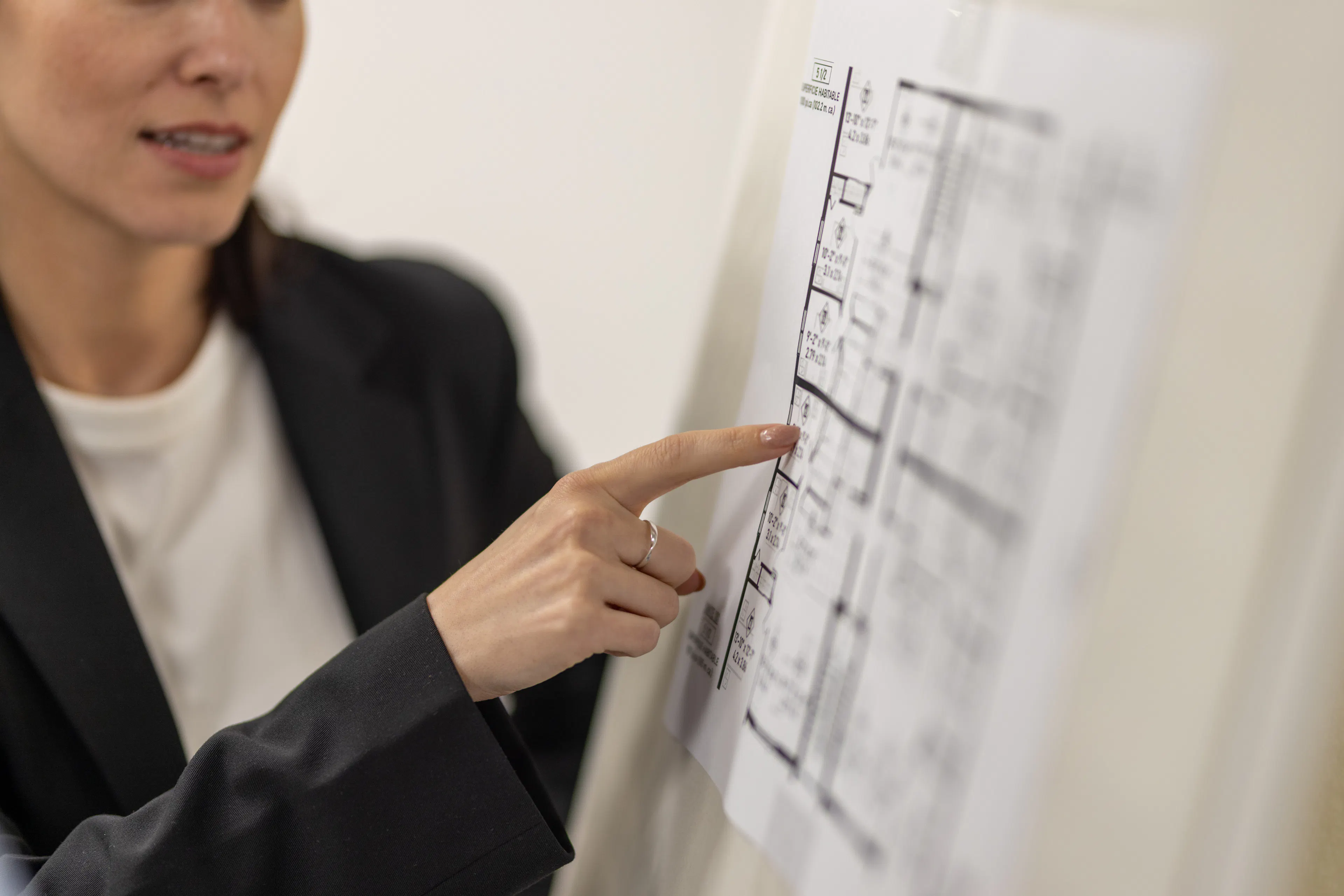 Une collaboratrice montrant un élément spécifique sur un plan d'immeuble