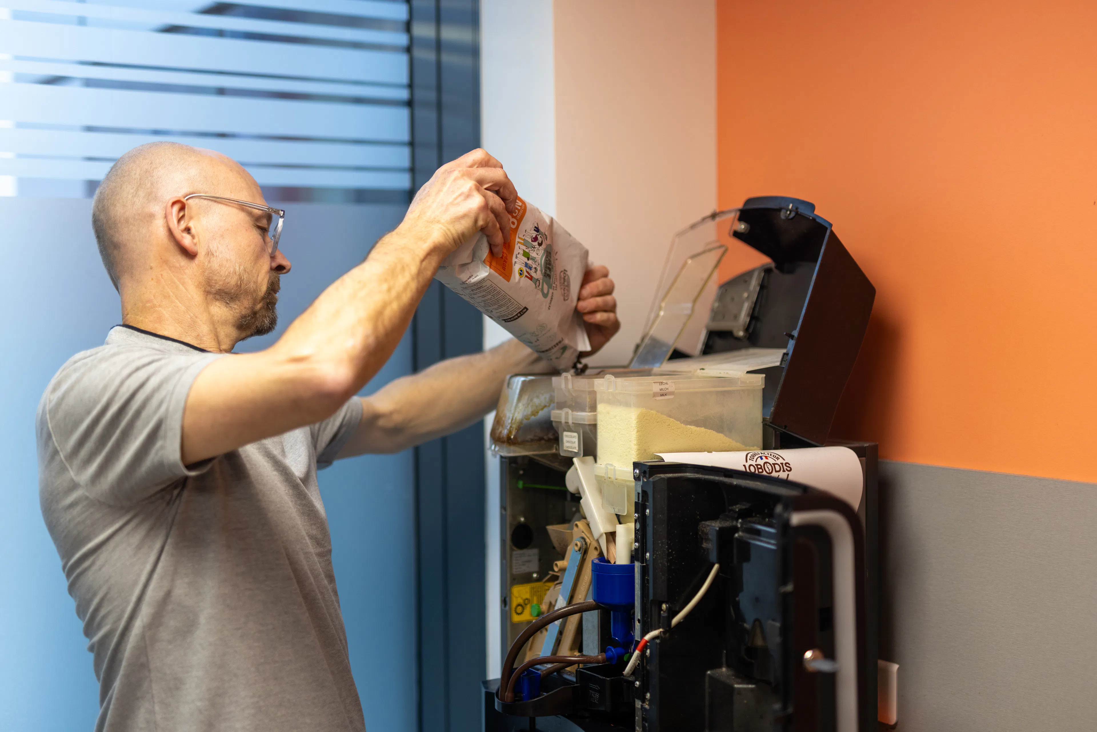 Un factotum réapprovisionne la machine à café