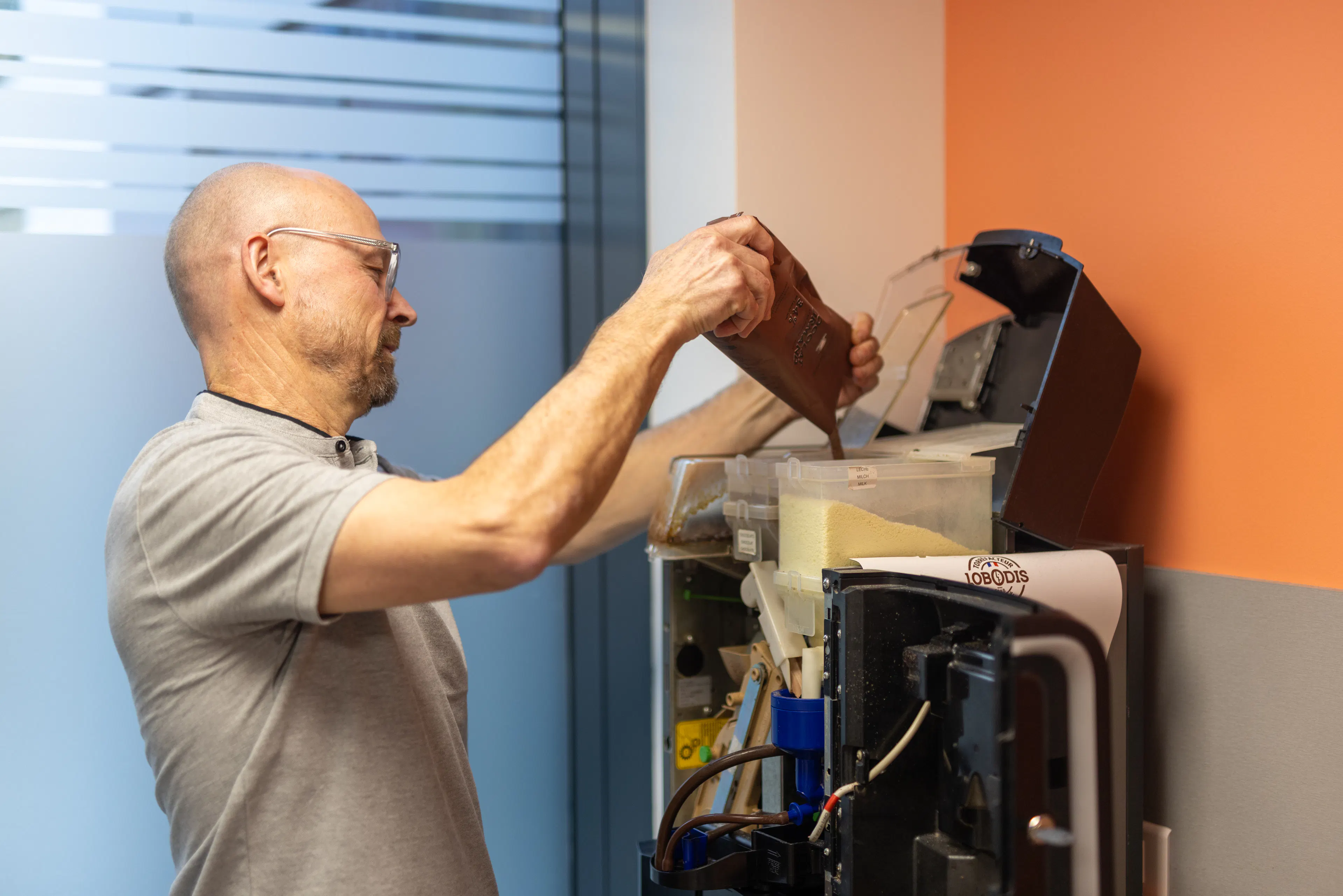 Un agent de maintenance réapprovisionne la machine à café