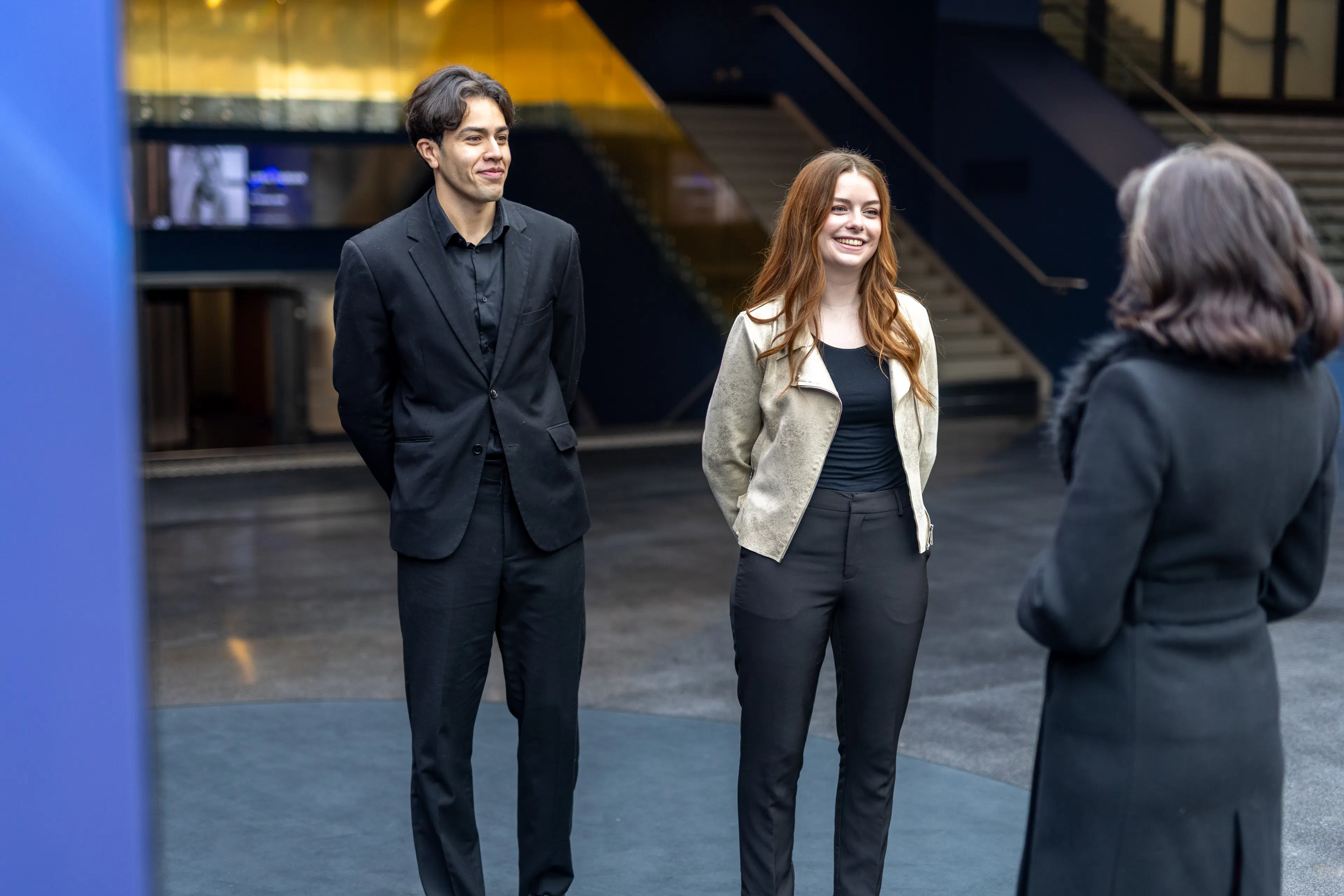 Deux hôtes accueillant un visiteur sur un lieu événementiel