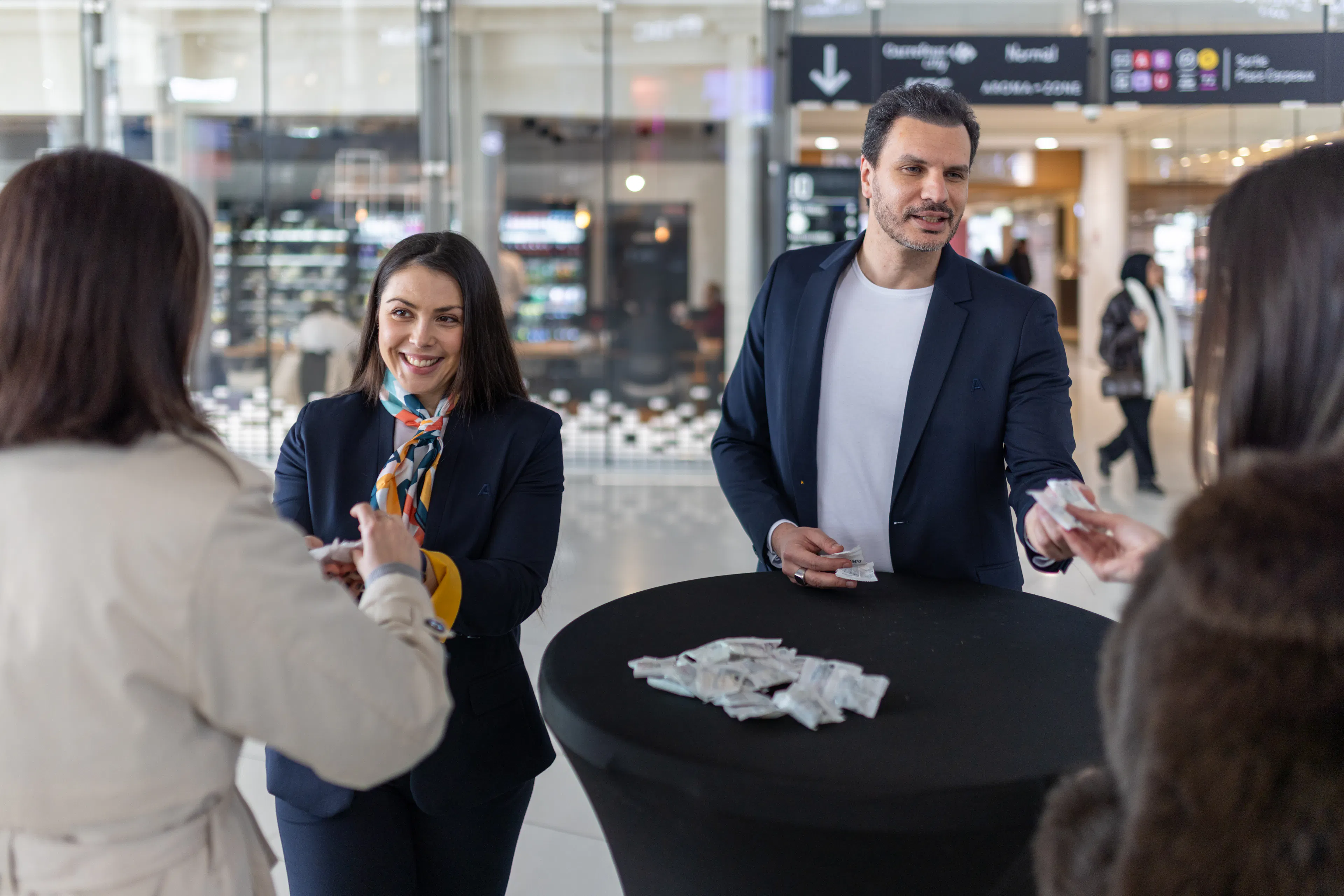 Deux hôtes distribuant un produit promotionnel à des visiteurs