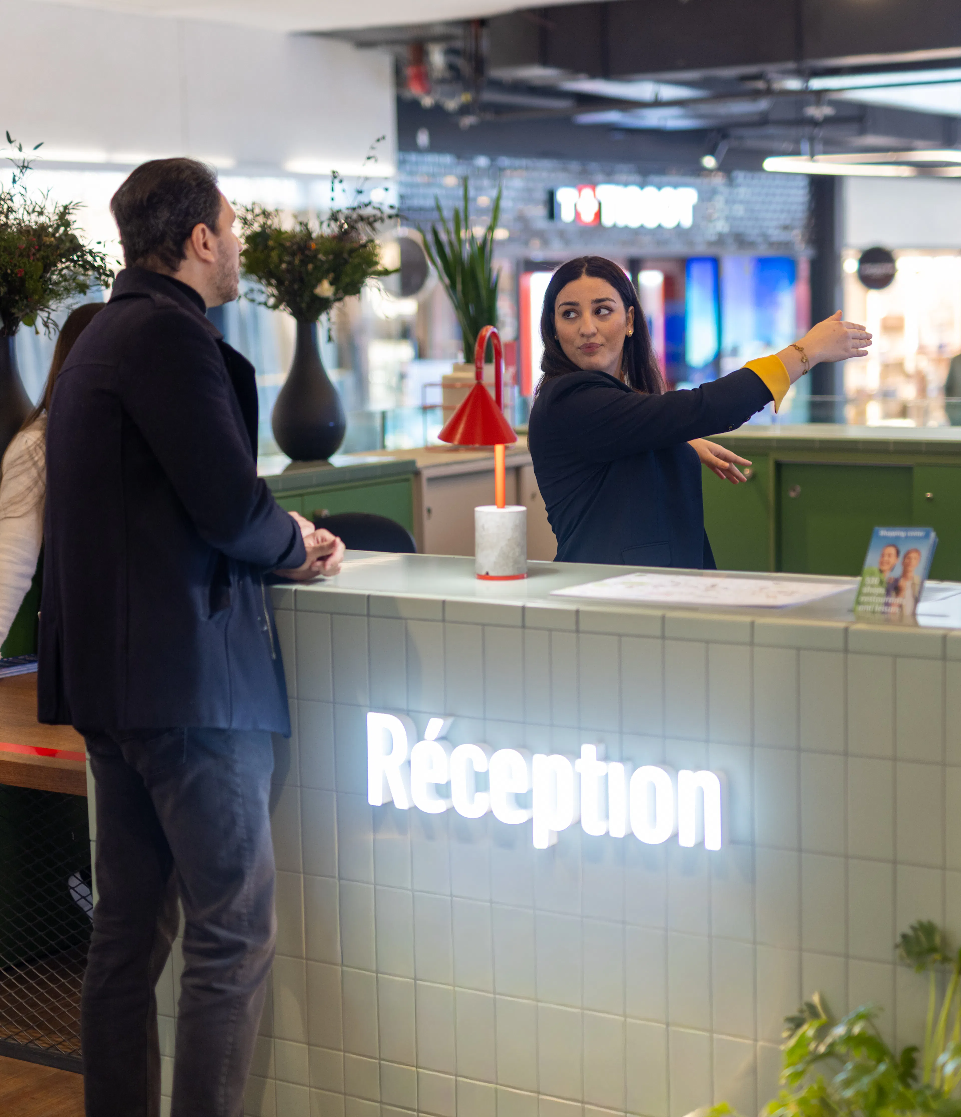 Une hôtesse d'accueil transmettant des informations sur l'orientation du centre commercial