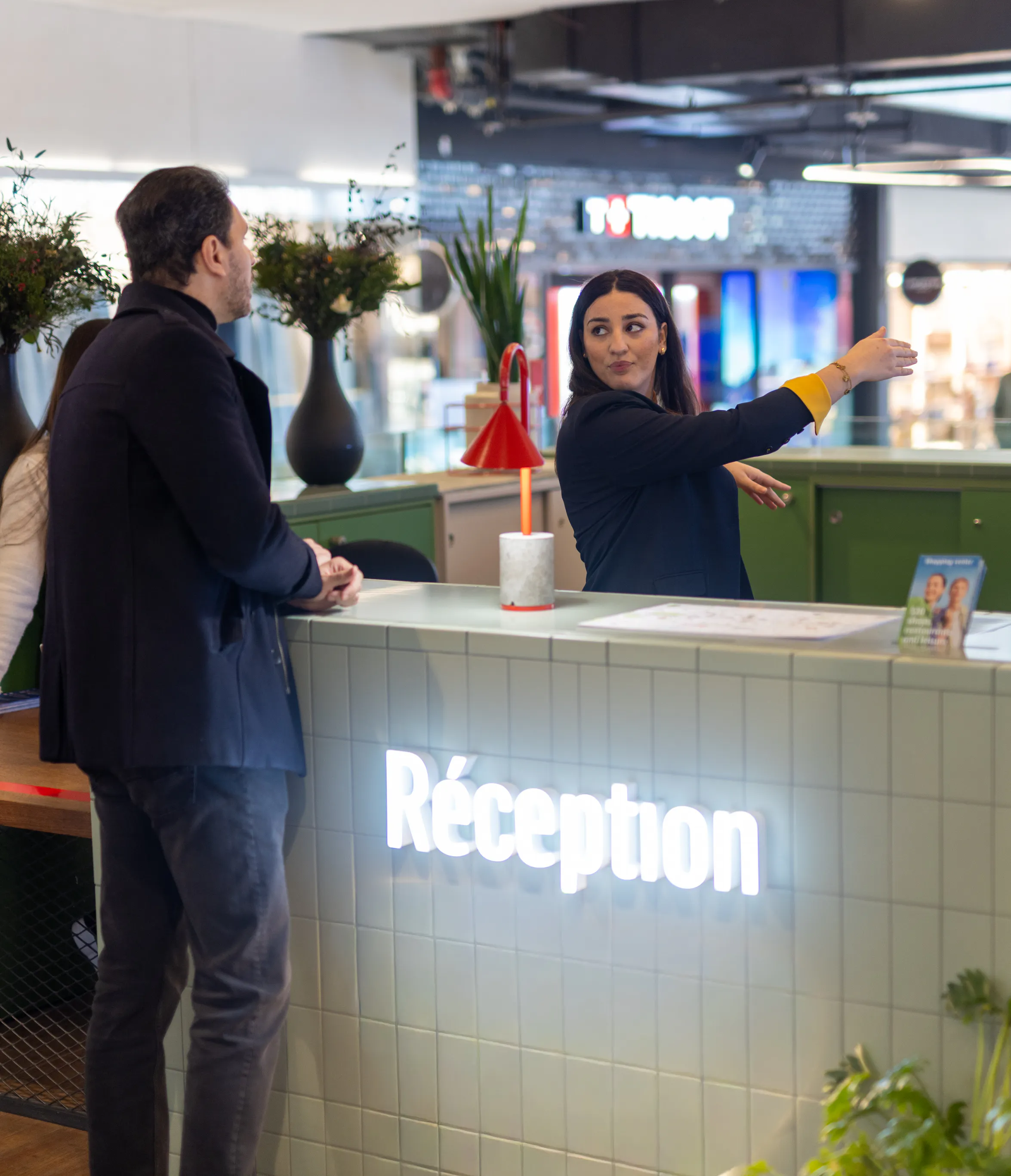 Une hôtesse d'accueil transmettant des informations sur l'orientation du centre commercial