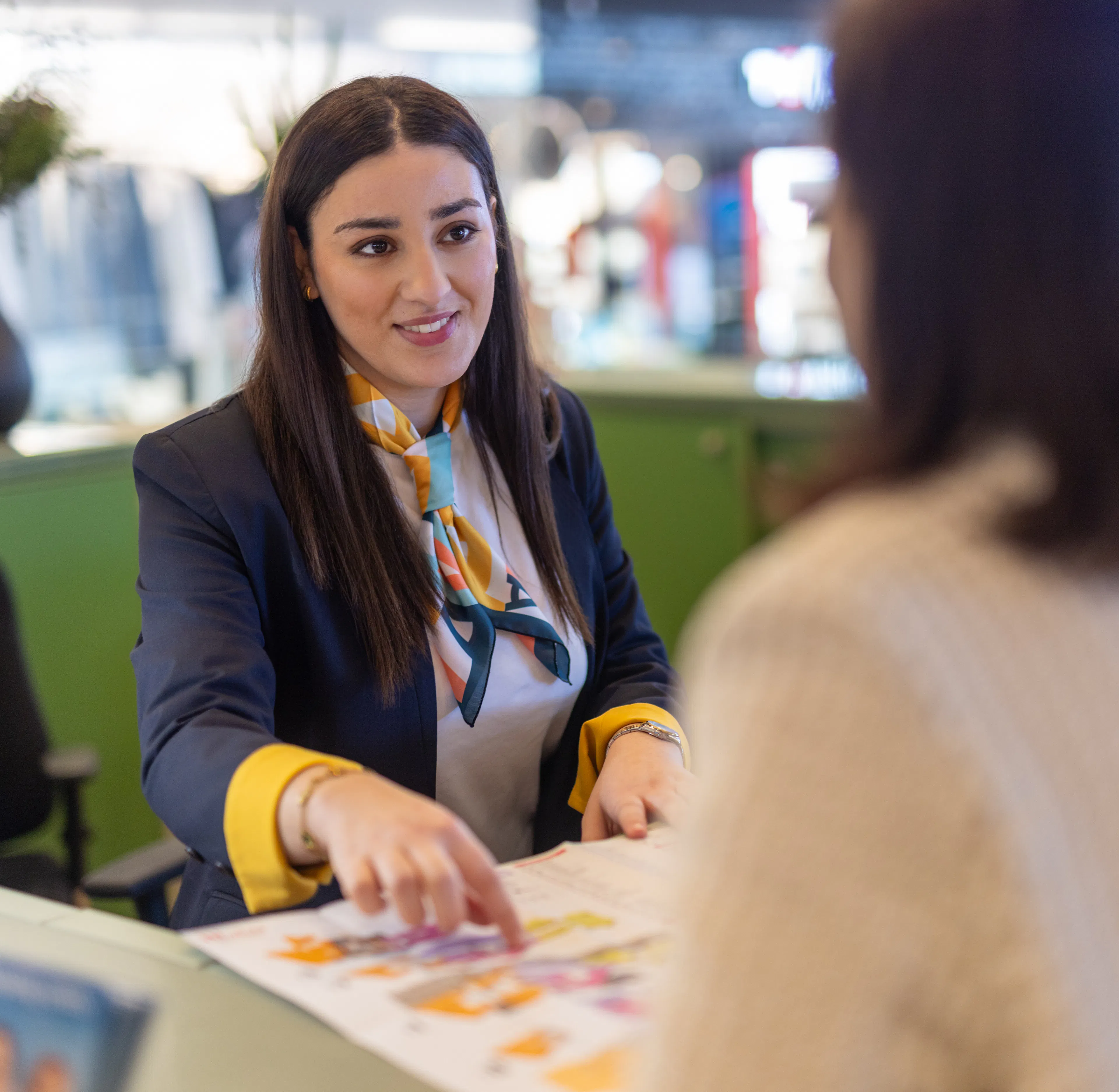 Une hôtesse d'accueil transmettant des informations sur le centre commercial à un visiteur