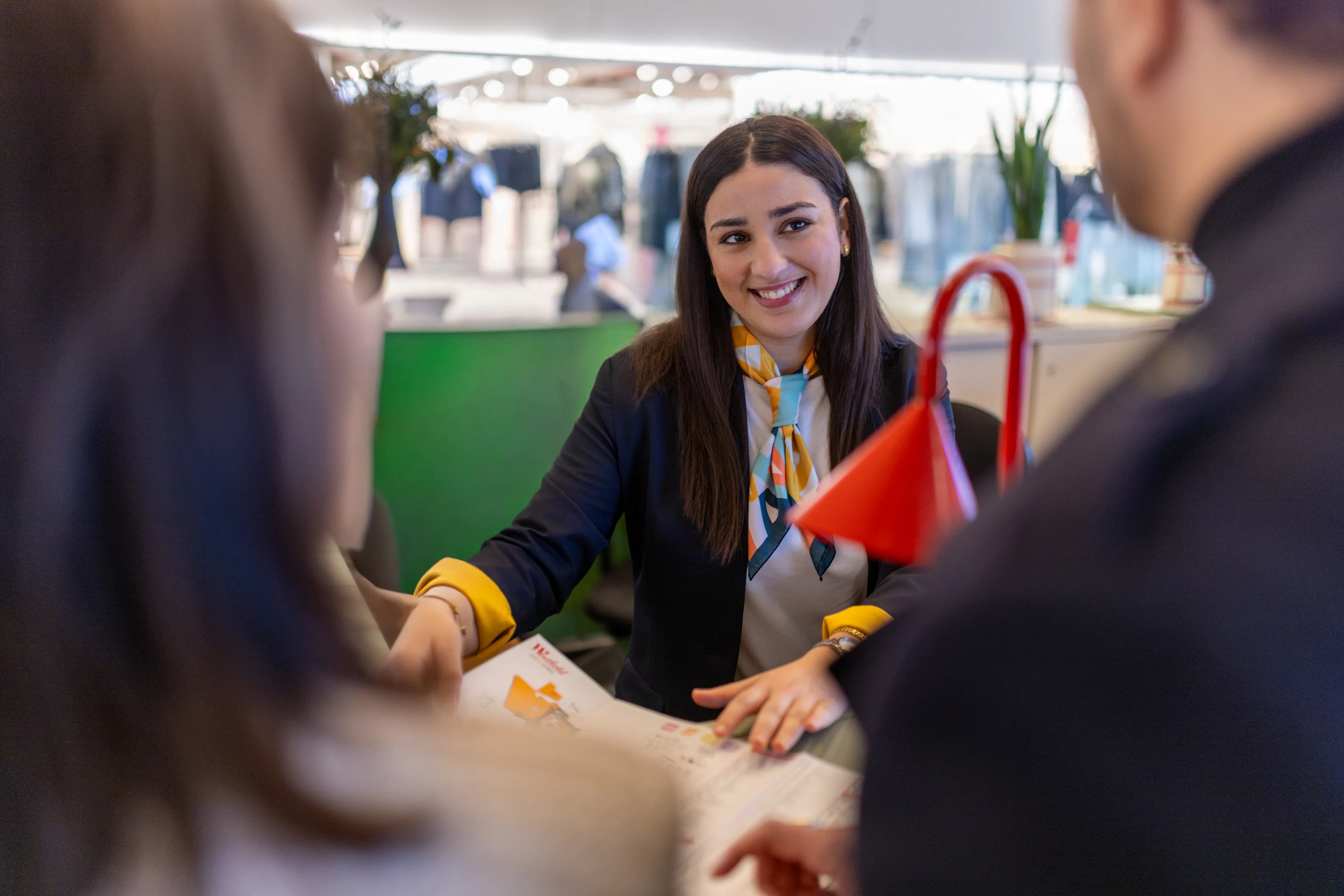 Une hôtesse d'accueil donnant des informations sur l'orientation du centre commercial à un visiteur