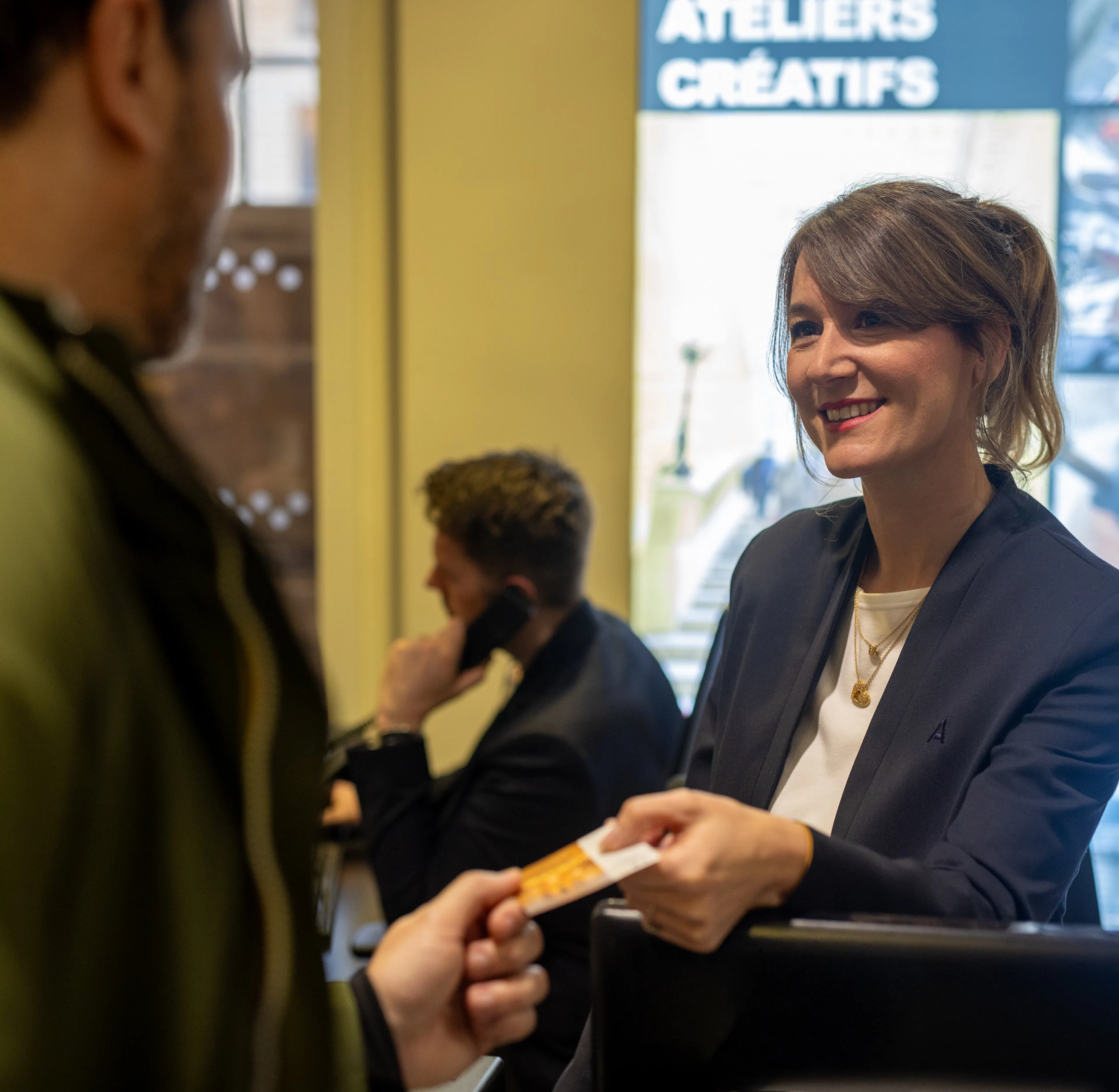Une hôtesse d'accueil remettant un billet à un visiteur dans un musée