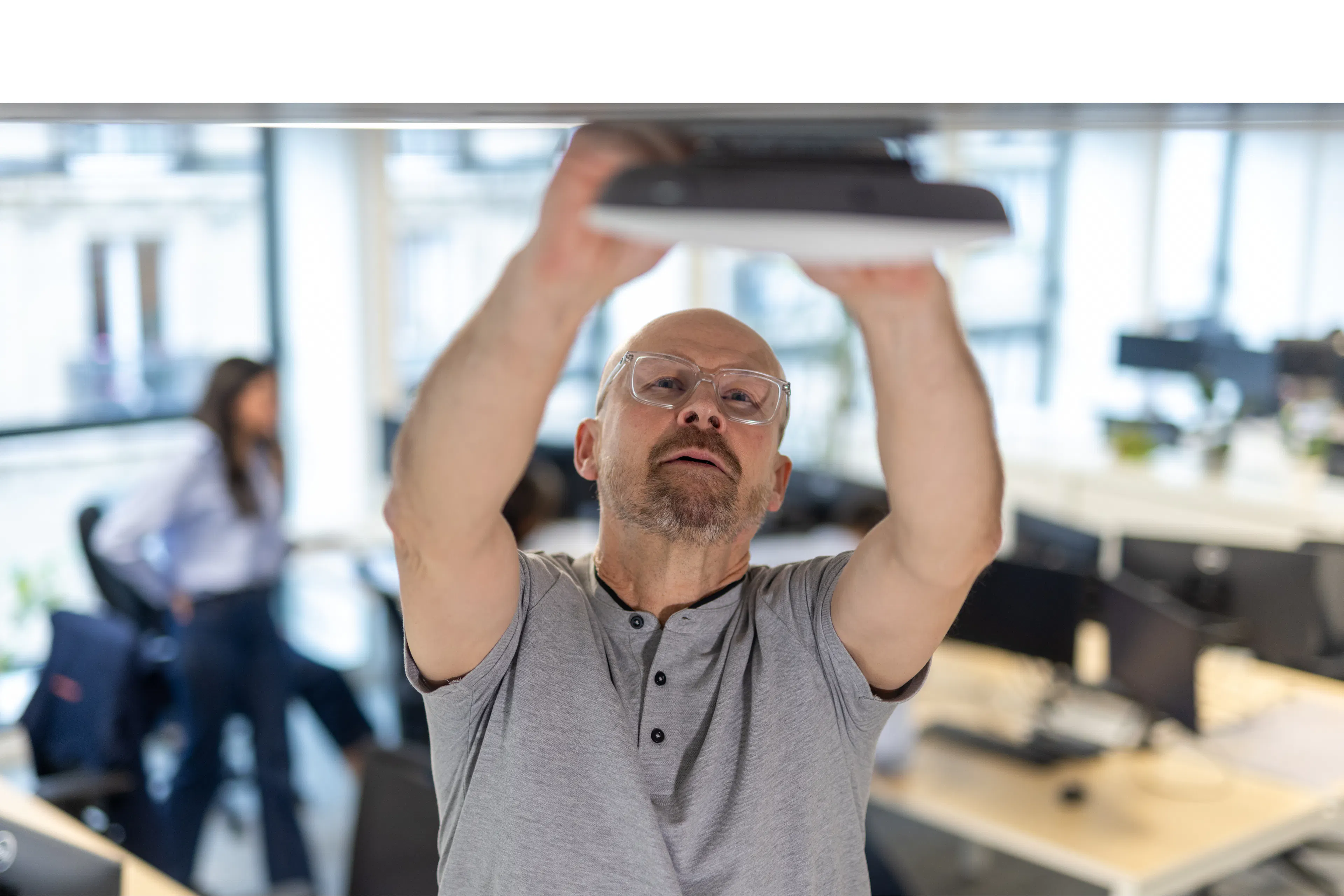 A maintenance agent repairing a wifi box in a work environment