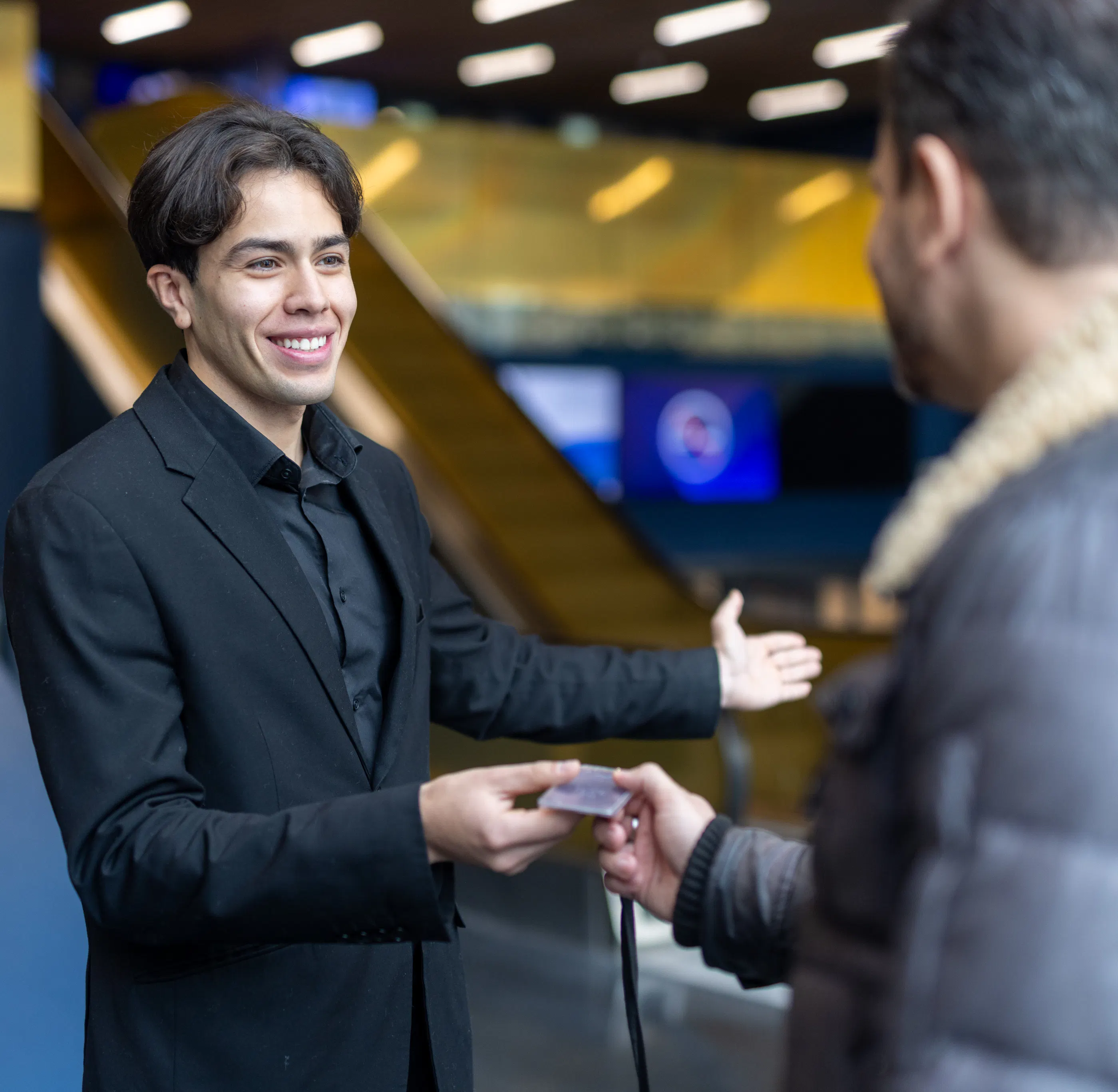 Une hôte remettant un badge d'accès à un visiteur sur un lieu événementiel