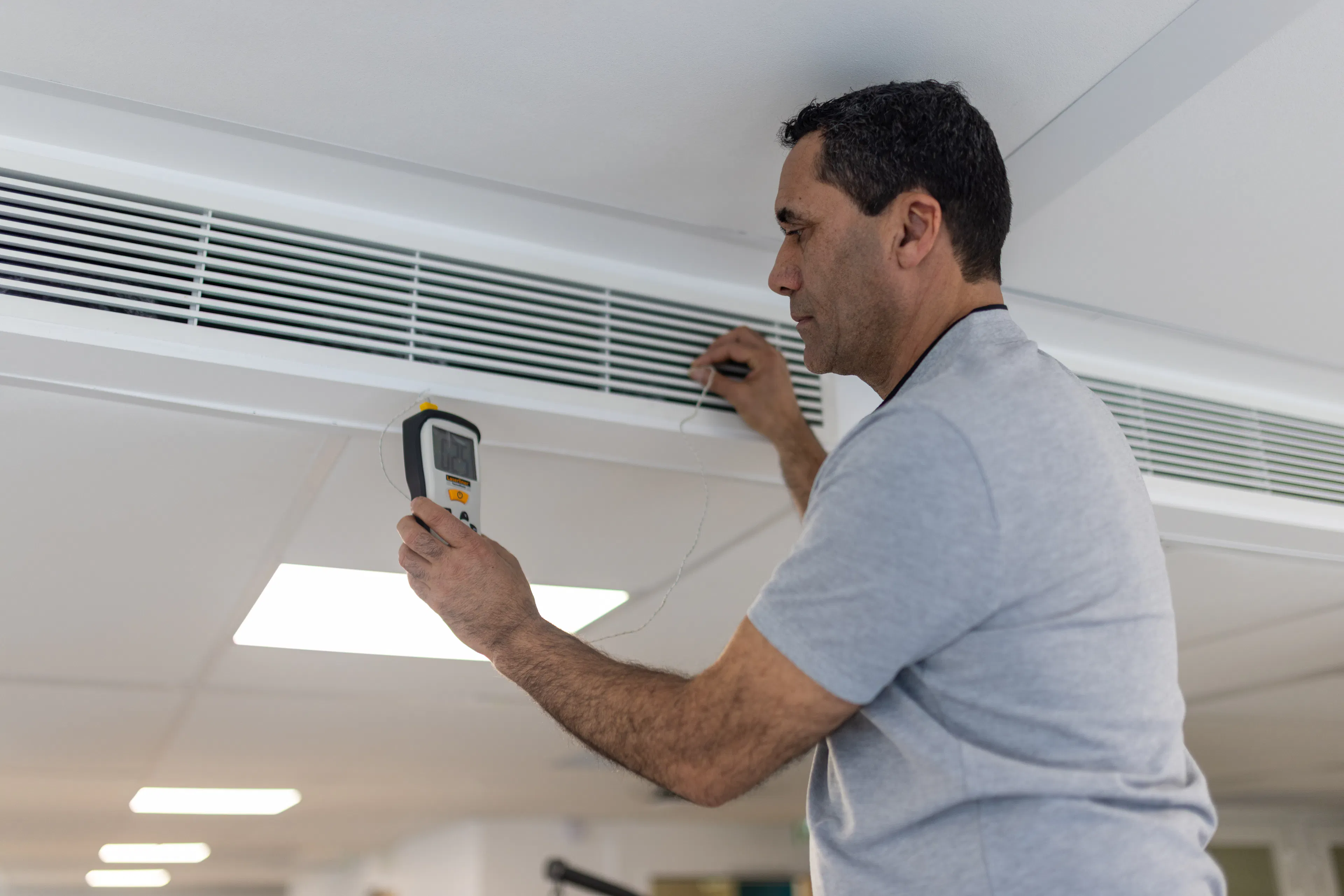 Un agent de maintenance réparant une climatisation