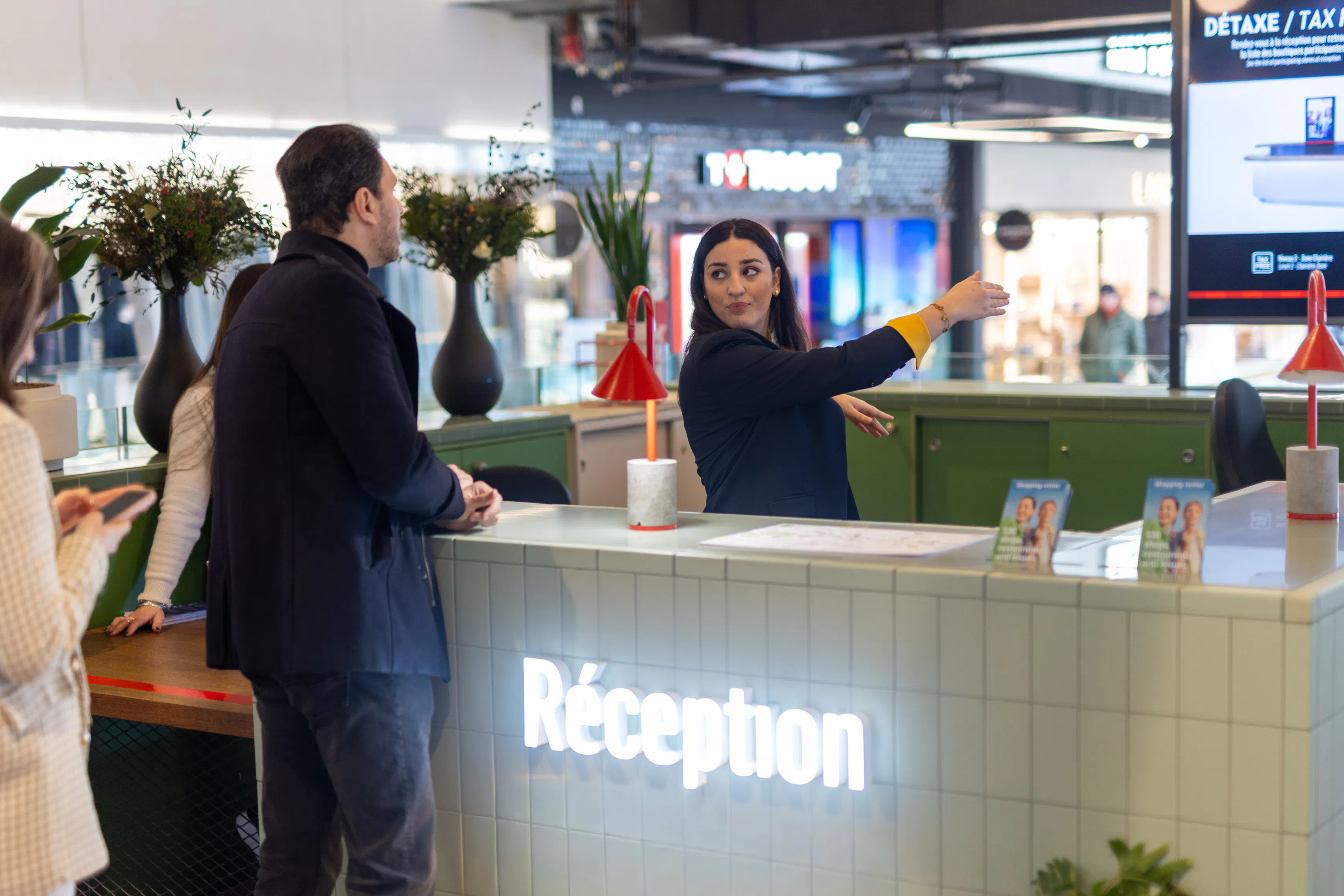 Une hôtesse d'accueil dans un centre commercial donnant des informations à un visiteur