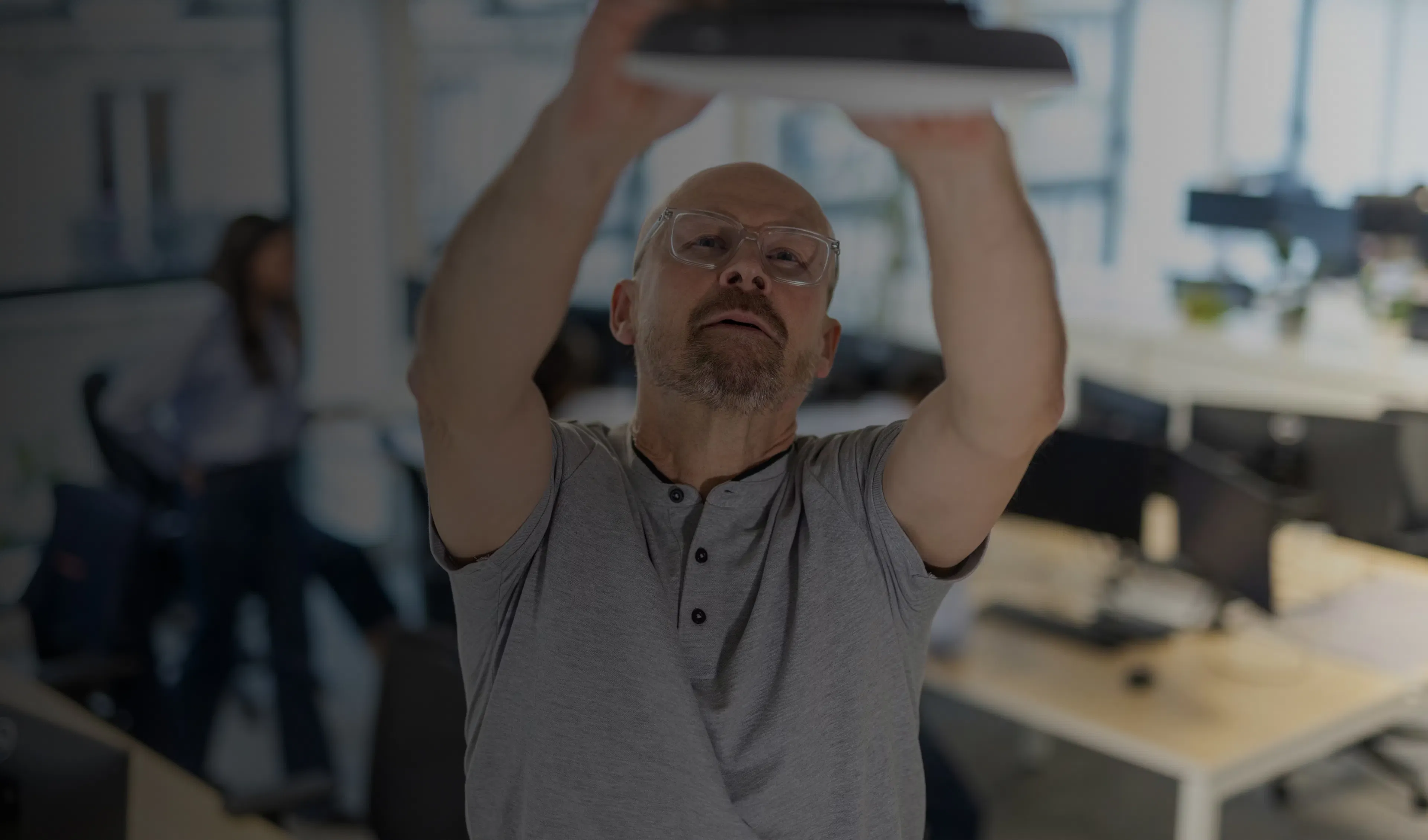 un agent de maintenance réparant une box wifi dans un plafond