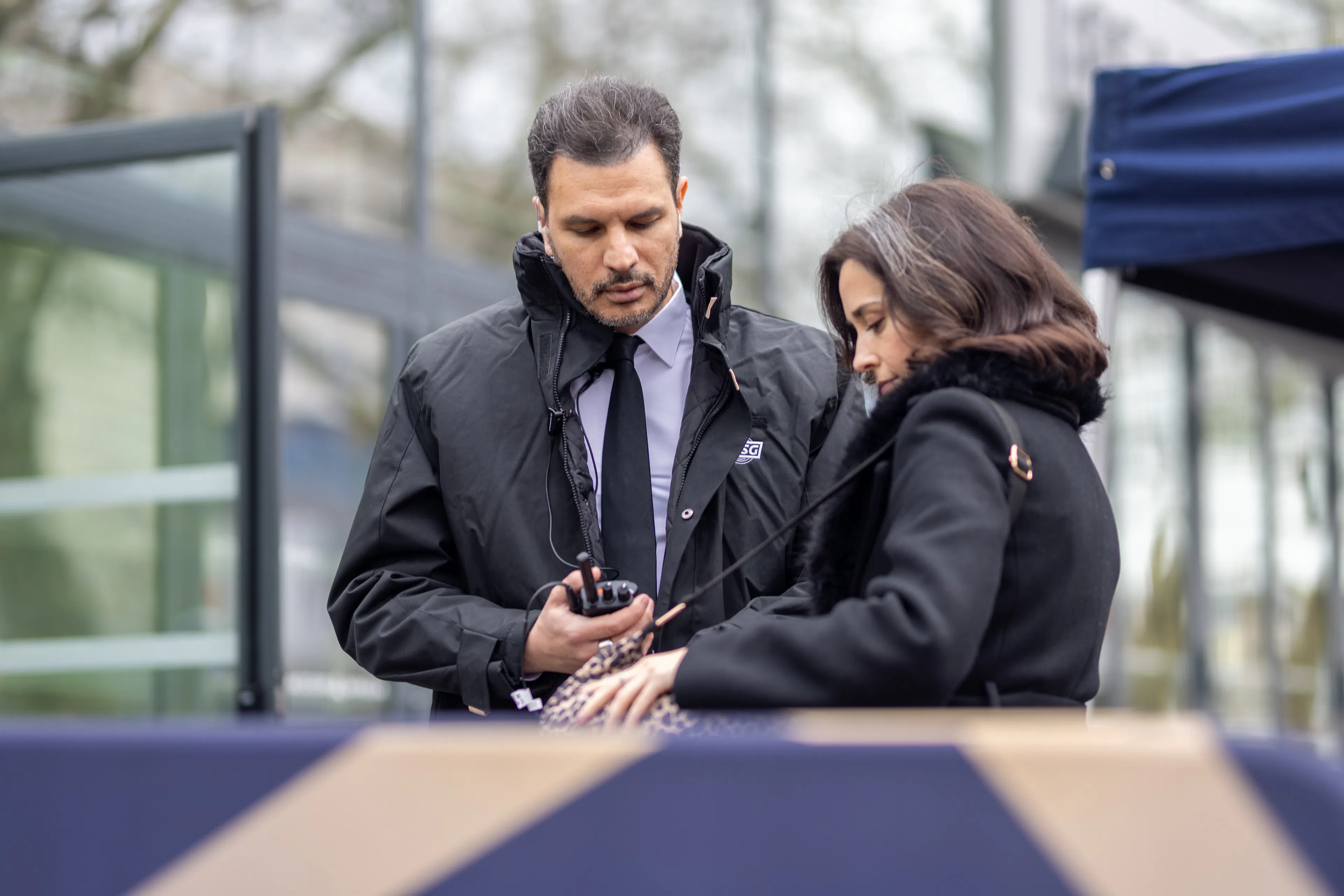 Un agent de sécurité contrôle le sac d'un visiteur à l'entrée du site événementiel