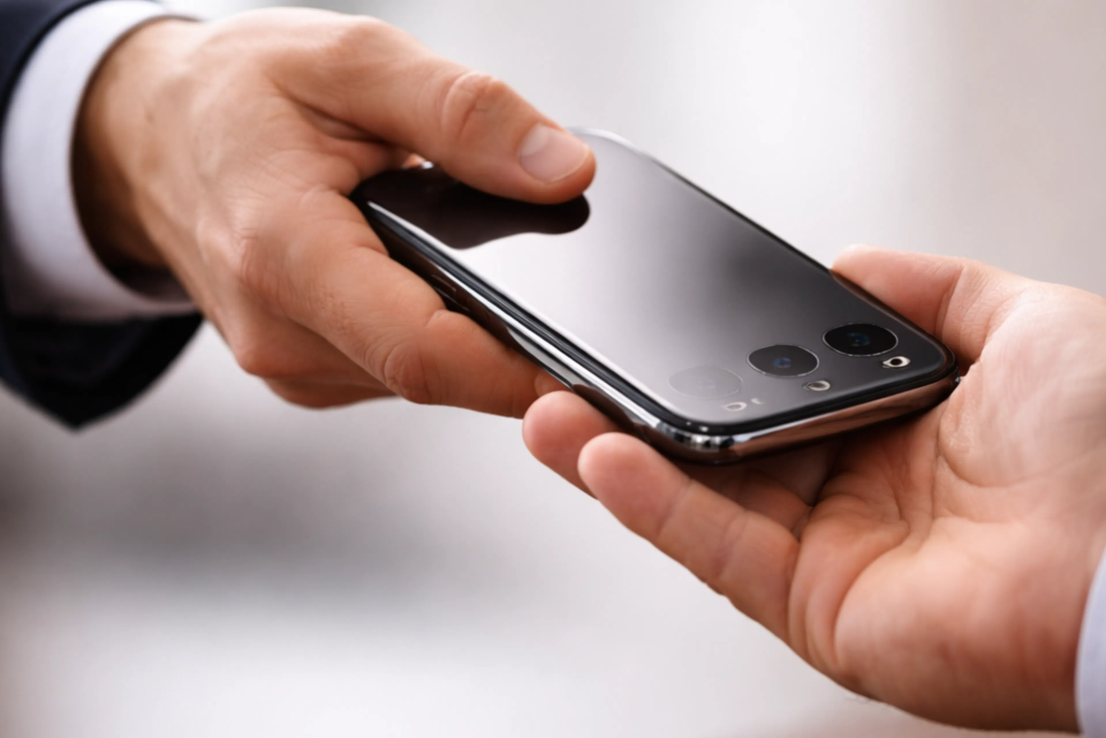 Une personne remettant un téléphone à un autre personne