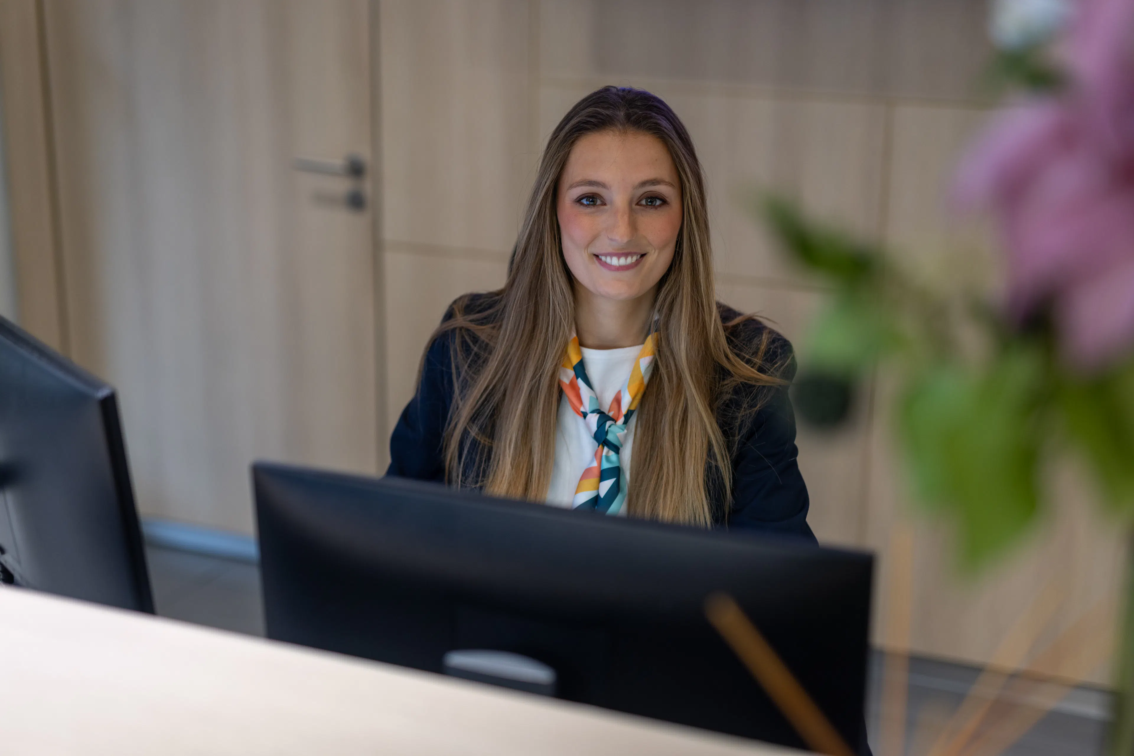 Une hôtesse d'accueil souriant devant son ordinateur