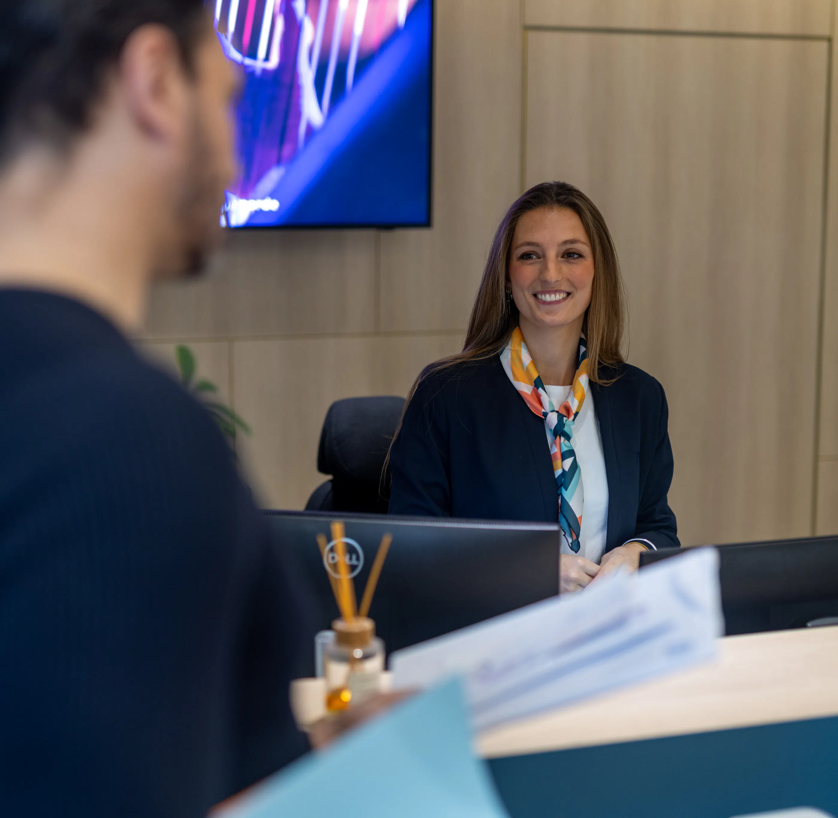 Une hôtesse d'accueil souriante remettant du courrier à un collaborateur