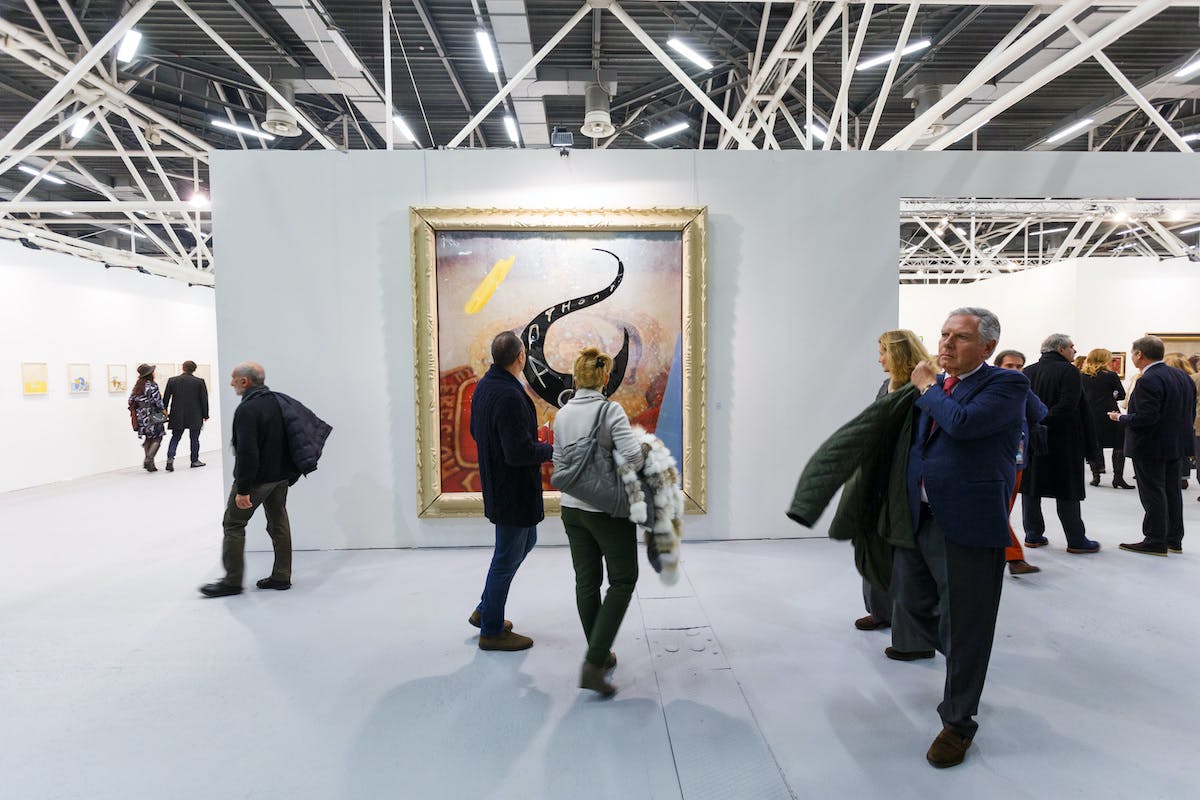 Art collectors in front of a Julian Schnabel painting at an art fair.