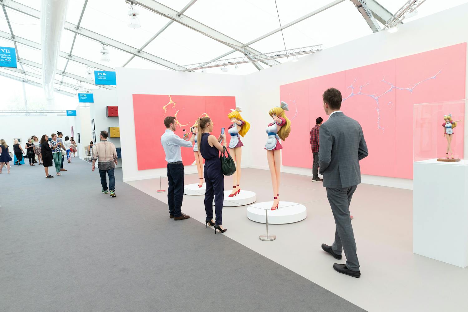 A photo of individuals at the Freize Art Fair admiring a booth with works by Takashi Murakami.