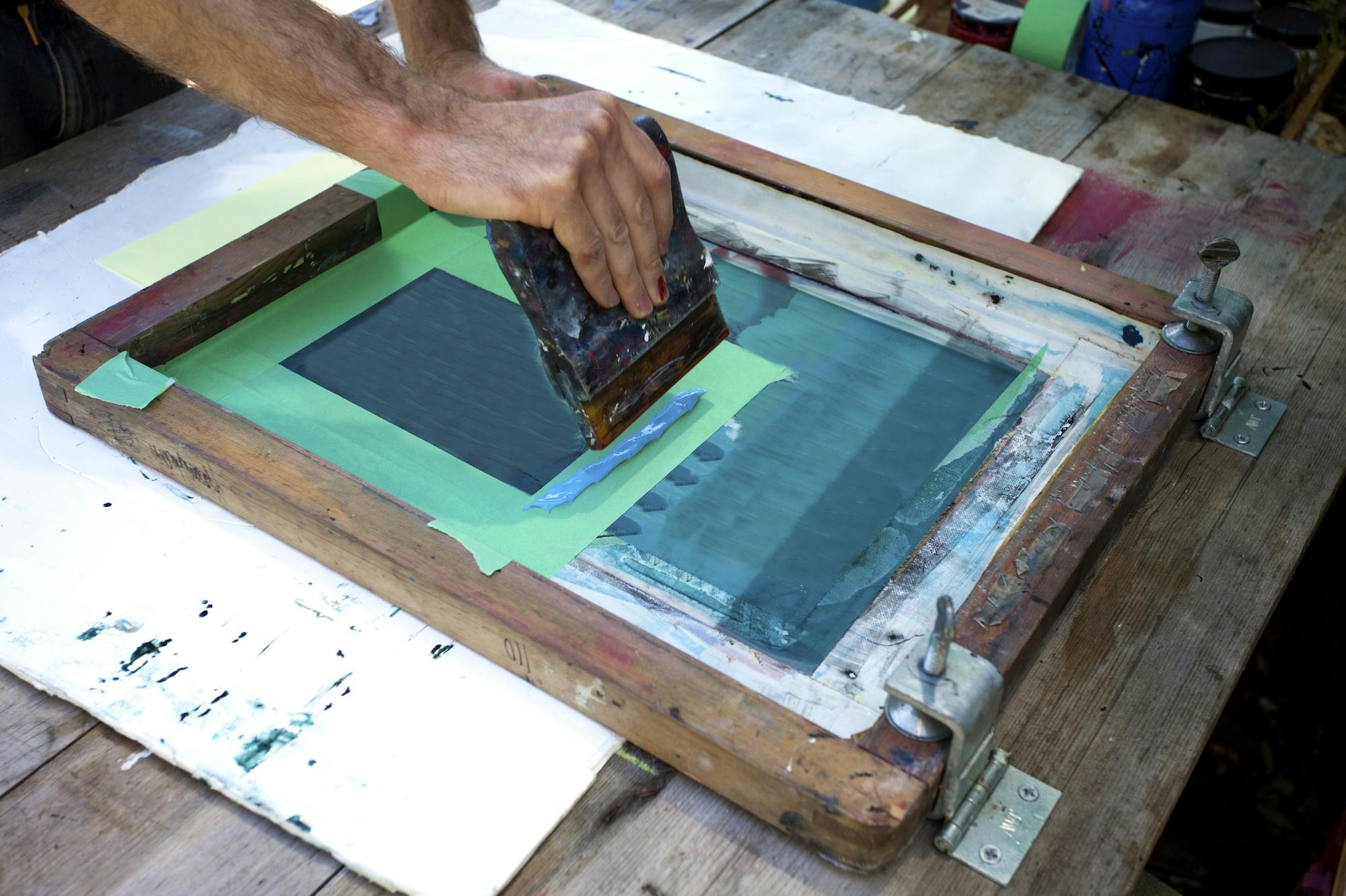 A photo of someone showing the screen printing process of printmaking.