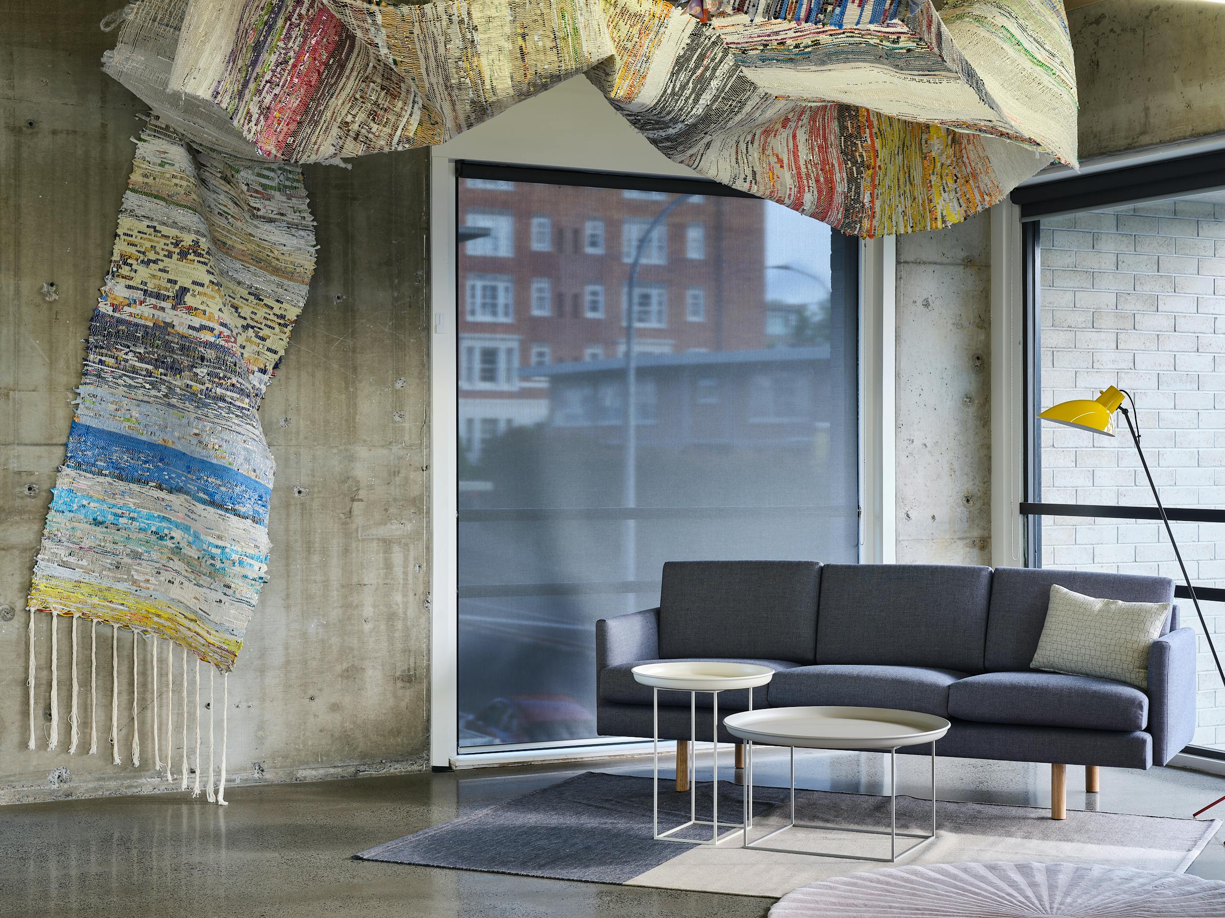 Karen Rubado's 'Under Intense Scrutiny' snakes above this casual seating arrangement, creating a welcoming zone in an otherwise hard, foreboding concrete office.