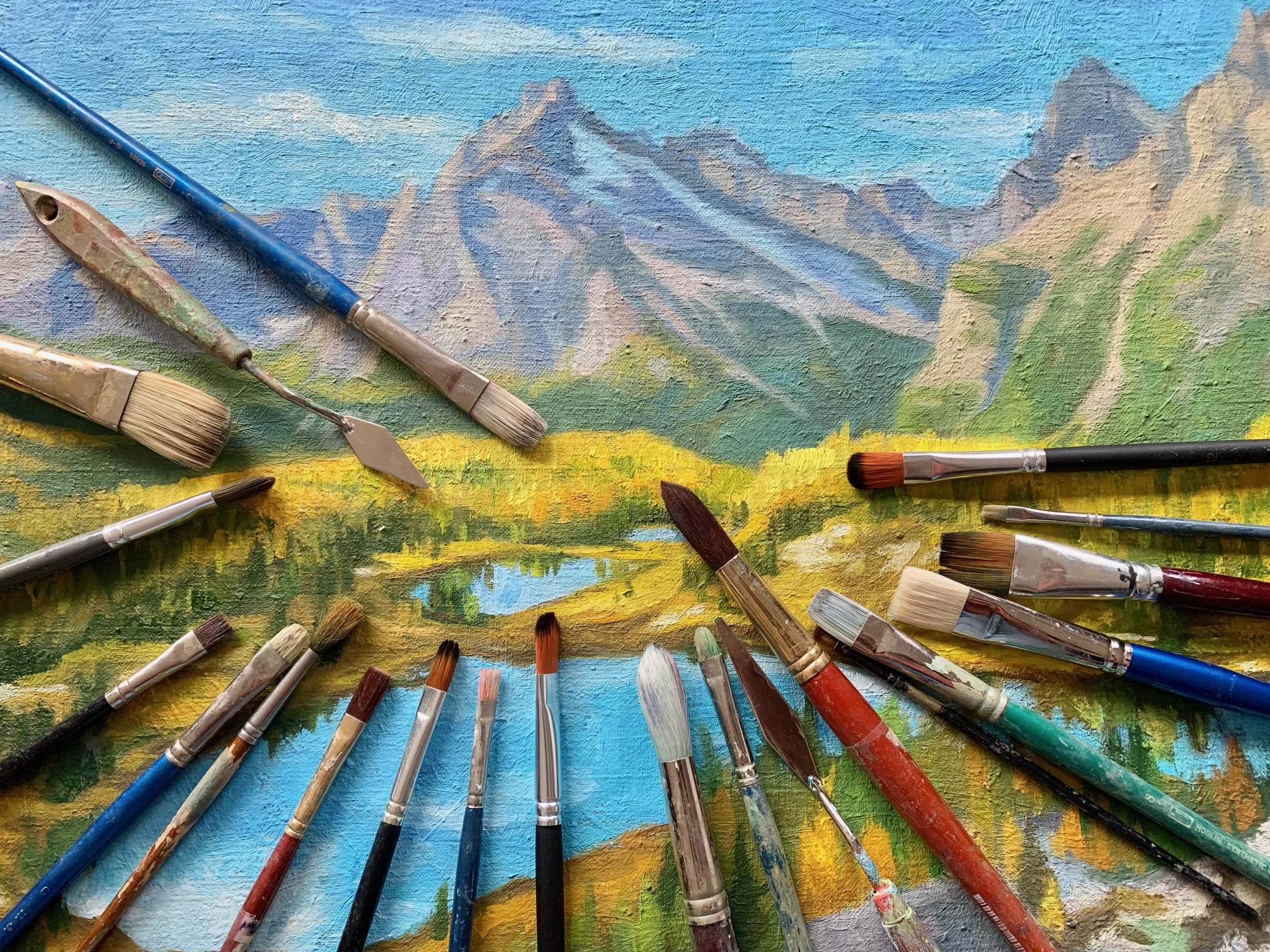 a variety of brushes on a painted canvas