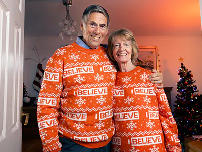 Smiling couple wearing Alzheimer's Research UK festive jumpers.