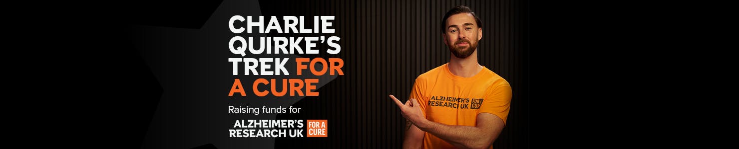 Charlie Quirke pointing to text that reads, Charlie Quirke's trek for a cure, raising funds for Alzheimer's Research UK.