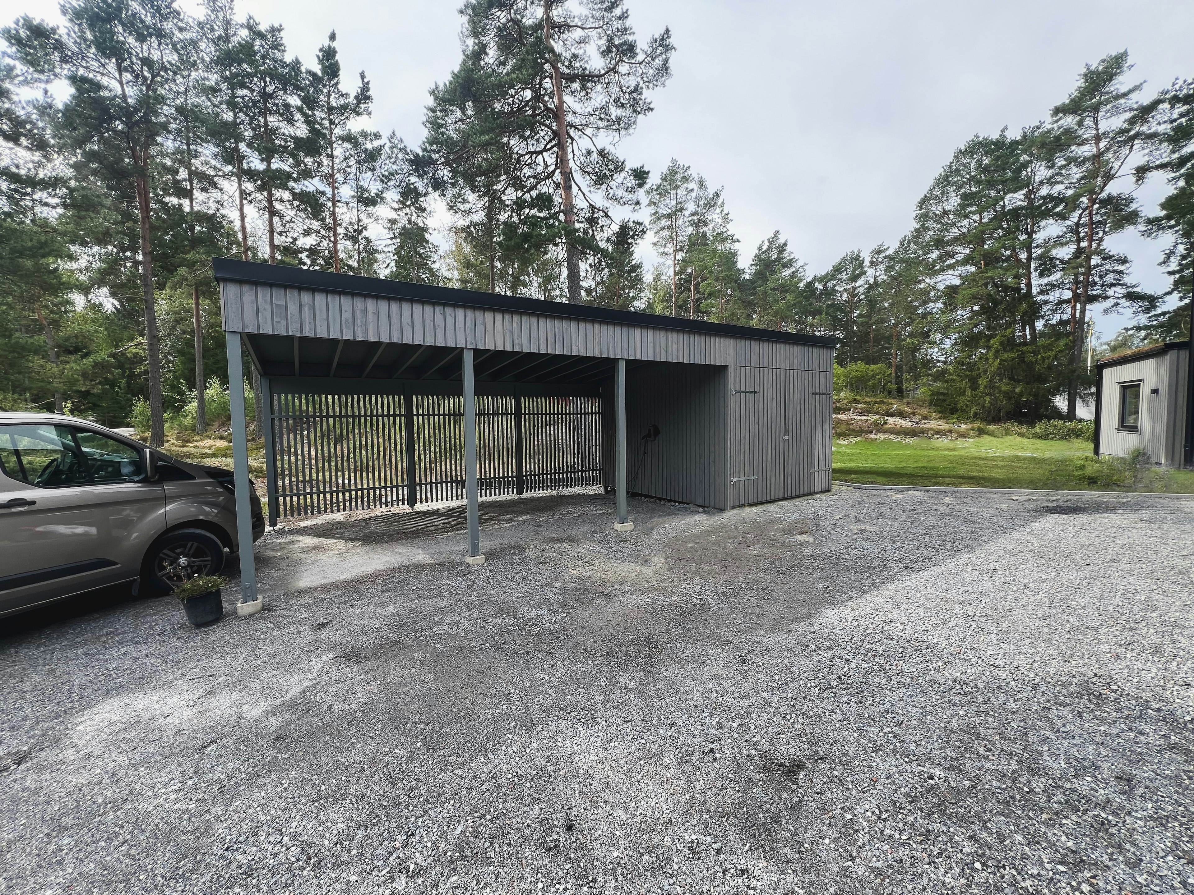 Carport i träpanel med förråd, en del av villatillbyggnad ritad av arkitektbyrå i Stockholm.