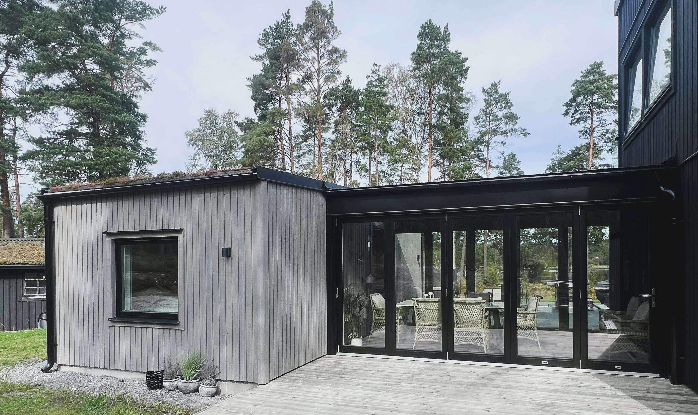 Exteriör vy av glasad gång som förbinder gästhus med huvudbyggnaden, arkitekt ritade hus i modern stil.