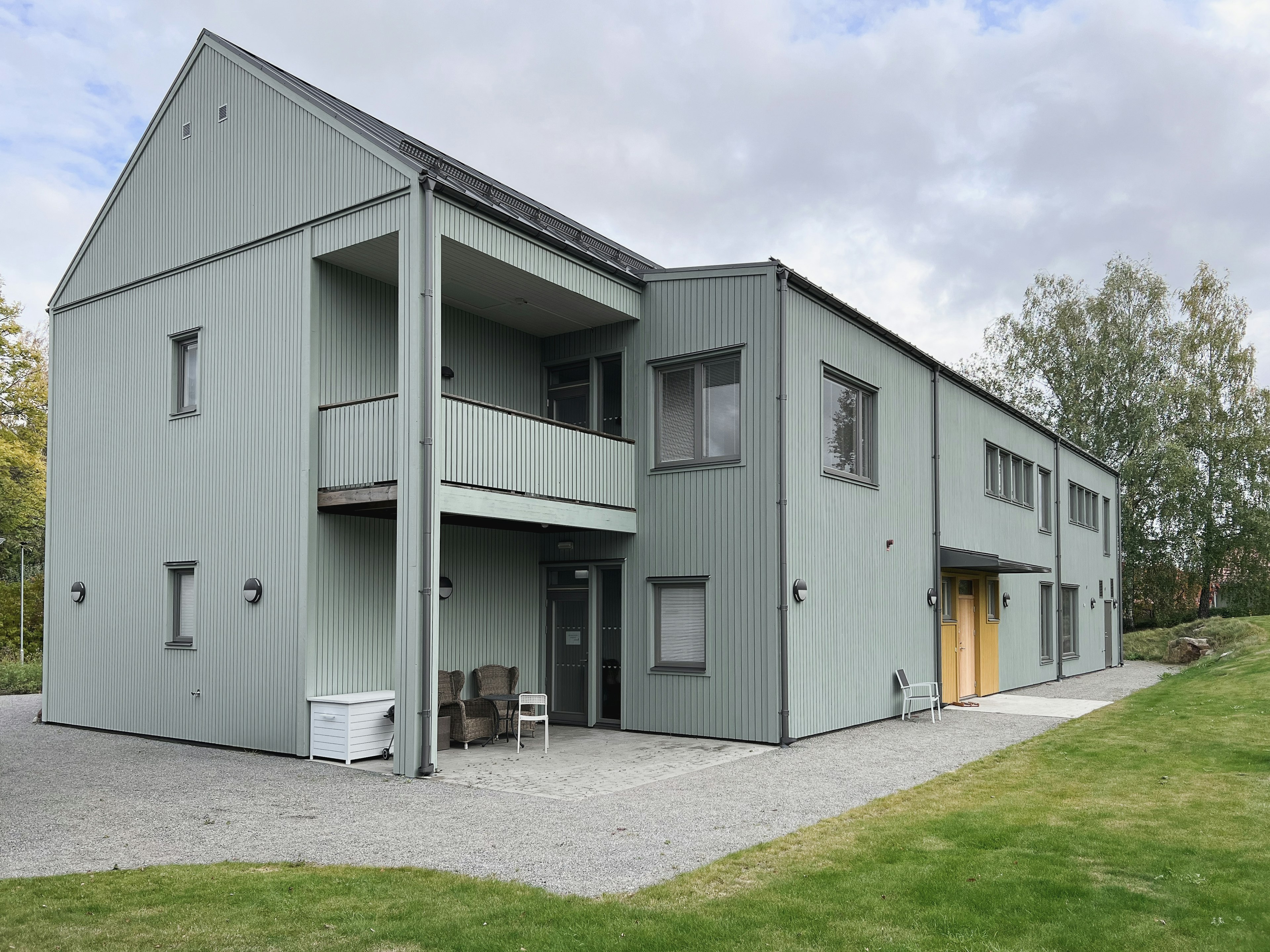 Gredelby LSS i Knivsta, framsida av modernt gruppboende ritat av arkitektkontor med träpanel i grön kulör.