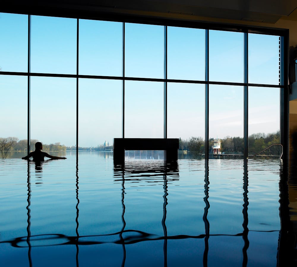 Women standing in the indoor pool staring out onto the lake