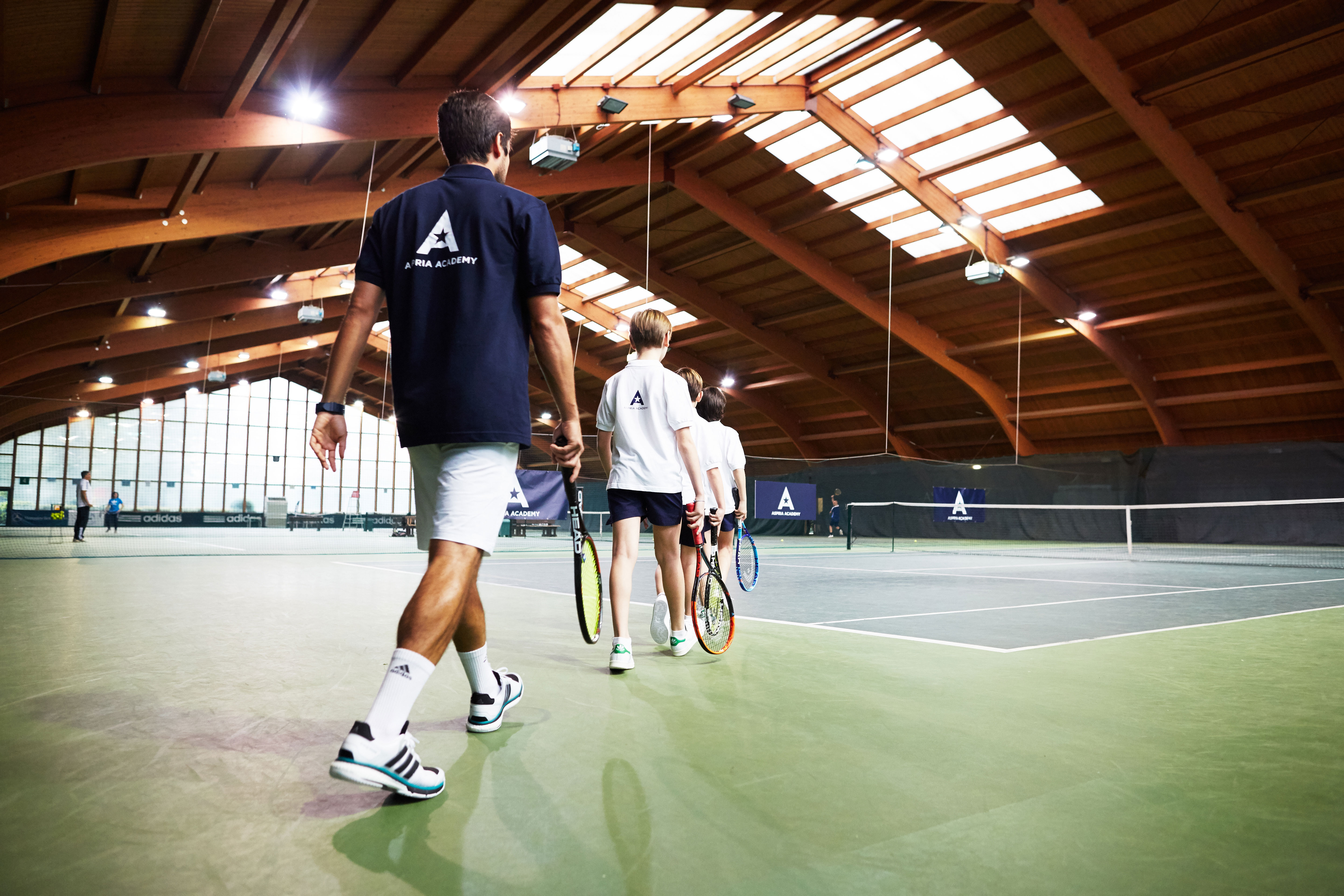 Coach walking out onto indoor tennis courts 
