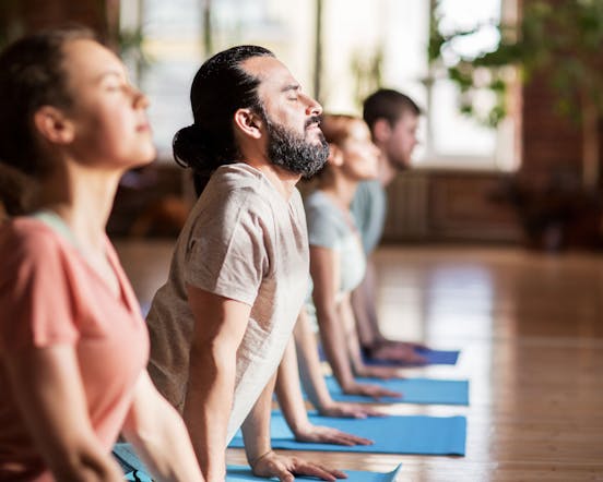 Women and man on yoga mat stretching
