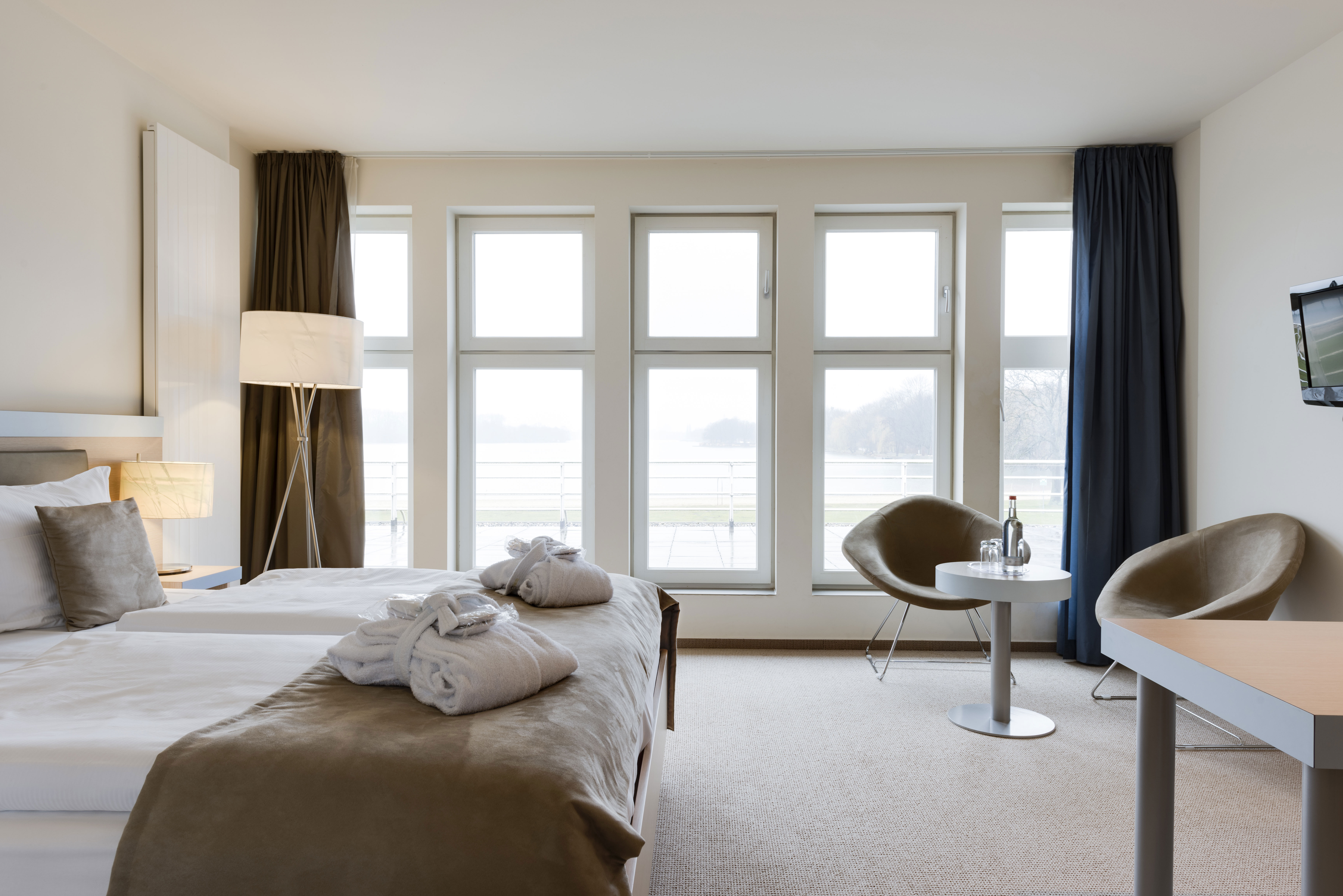 Folded white towels on top of made hotel beds 