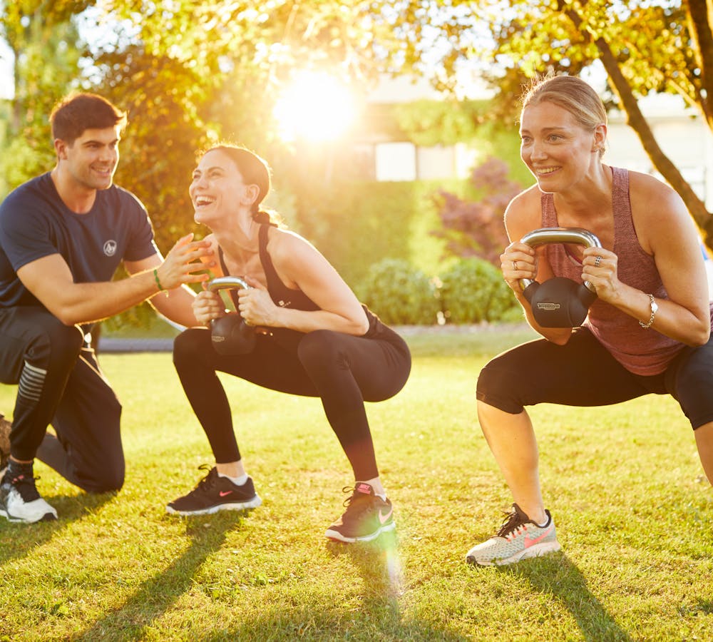 Male instructor with two females squatting holding kettlebells