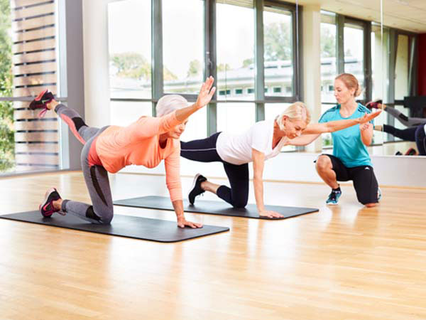 Two women on yoga mats stretching arms in front of them