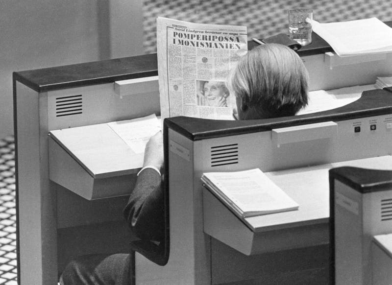 Finansminister Gunnar Sträng sitter i sin riksdagsbänk och läser Astrid Lindgrens "Pomperipossasaga" införd i Expressen 10 mars 1976. 