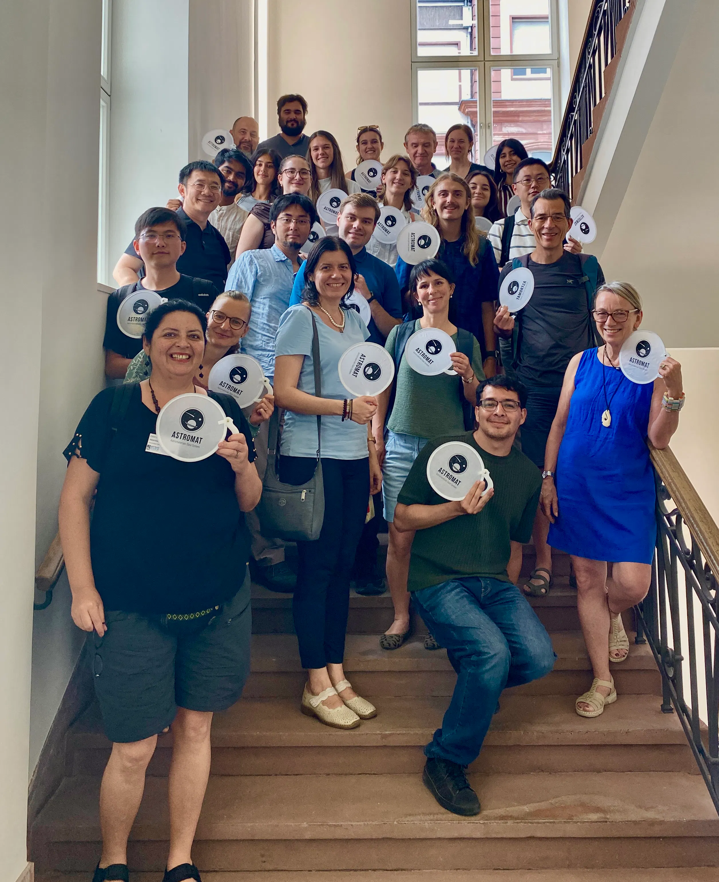 Group photo of the workshop participants on the venue stairs with their Astromat fans.