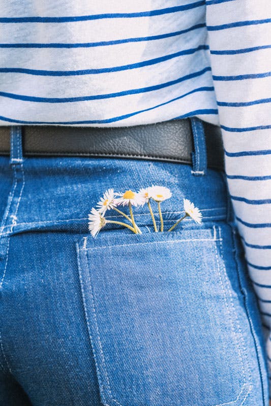 gros plan sur la poche arrière d'un jean avec la ceinture mode vegan rosie et des pâquerettes