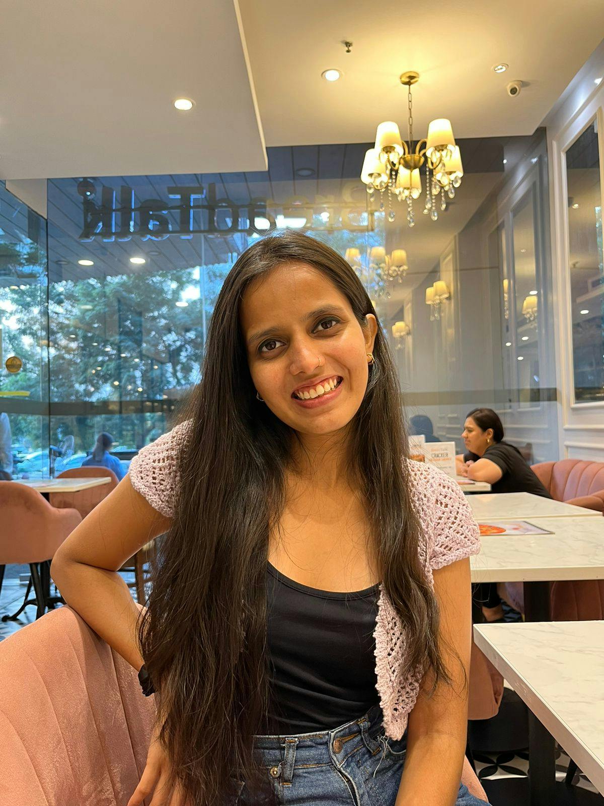 Picture of Divya sitting in a nice cafe