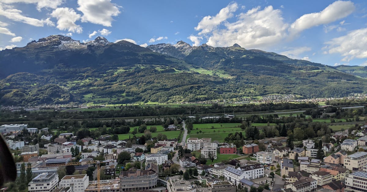 A view of city buildings and green mountains during day time in Liechtenstein.