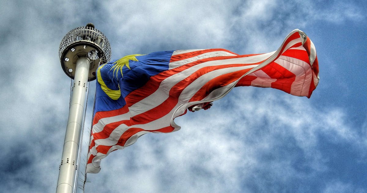 Red and blue flag of Malaysia waving in the wind during daytime.