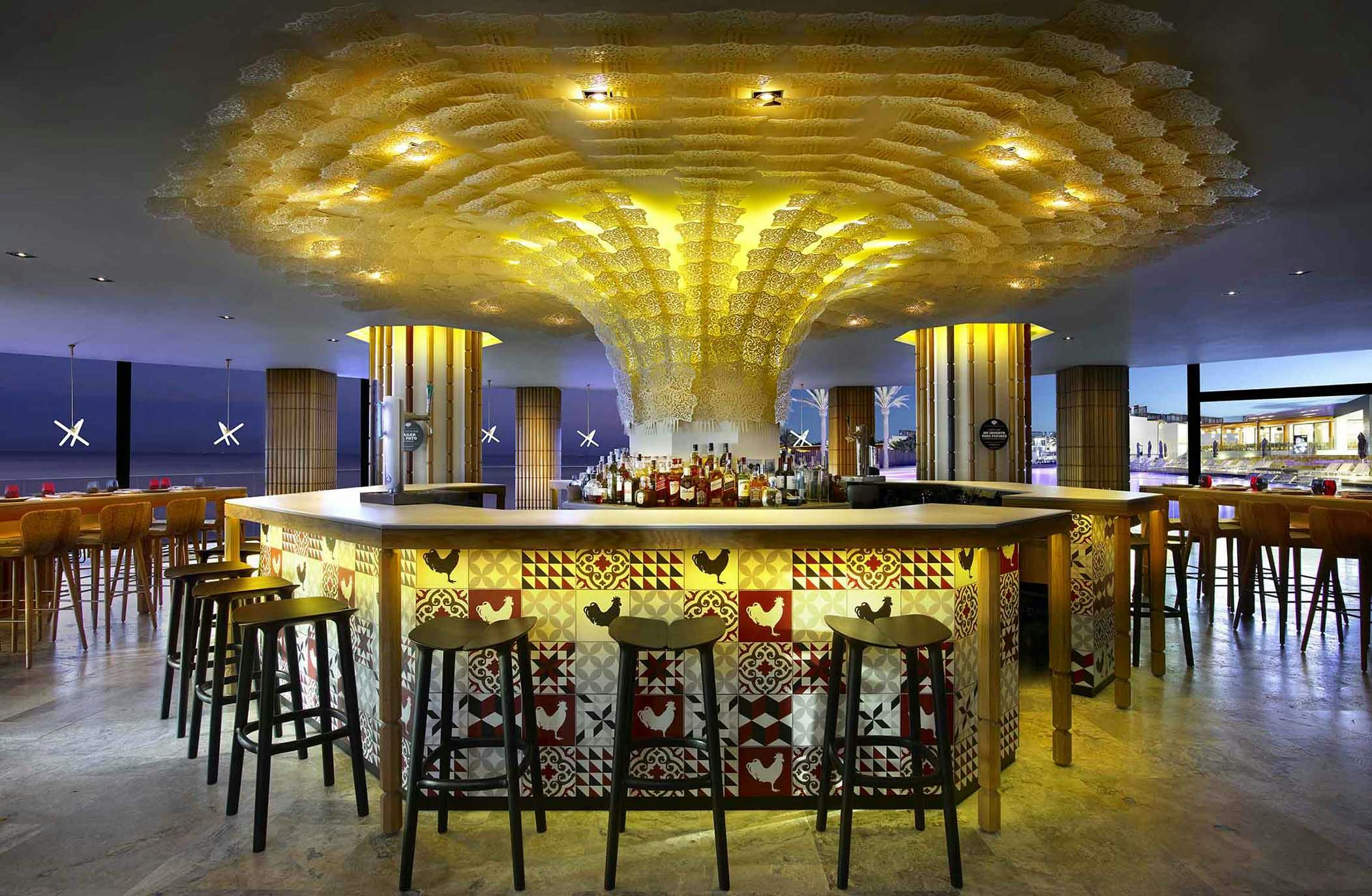 Center bar inside a resrtaurant with stools surrounding the bar.