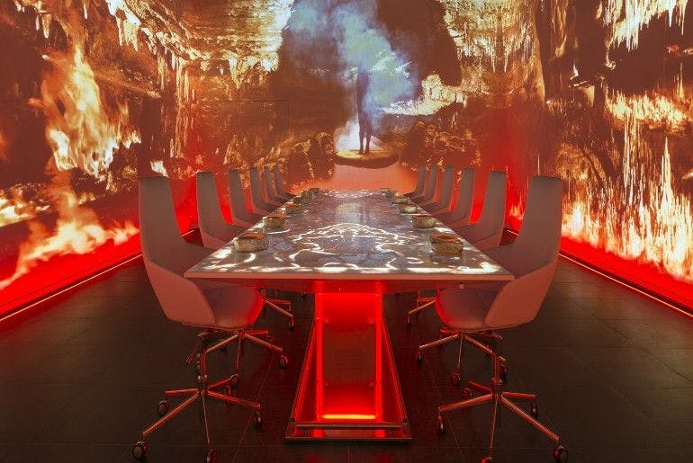 A room filled with a table and chairs and a background of digital flames.