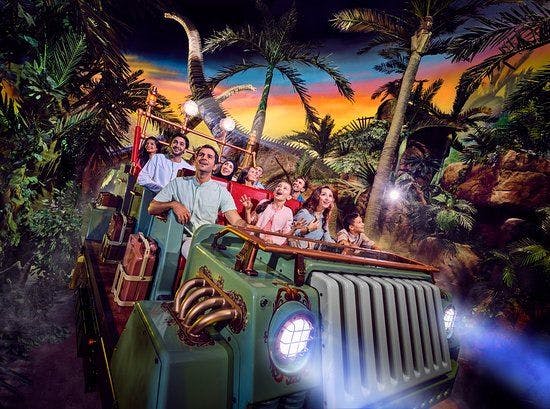 People inside a car traveling through a jungle themed park.