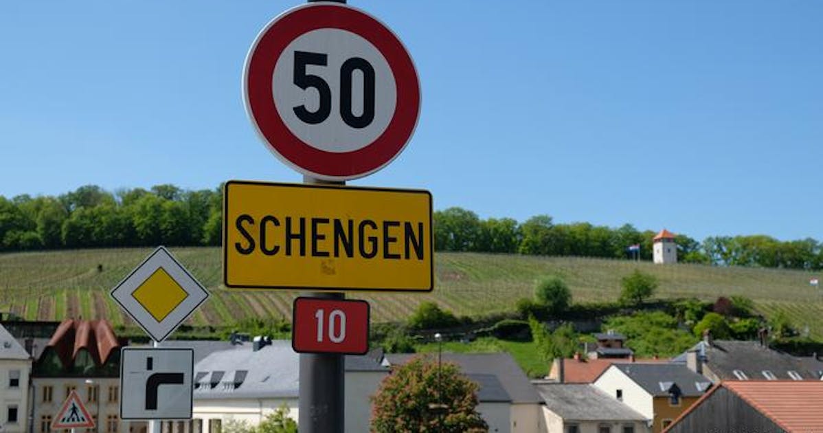 A view of beautiful houses with a Schengen road sign during daytime