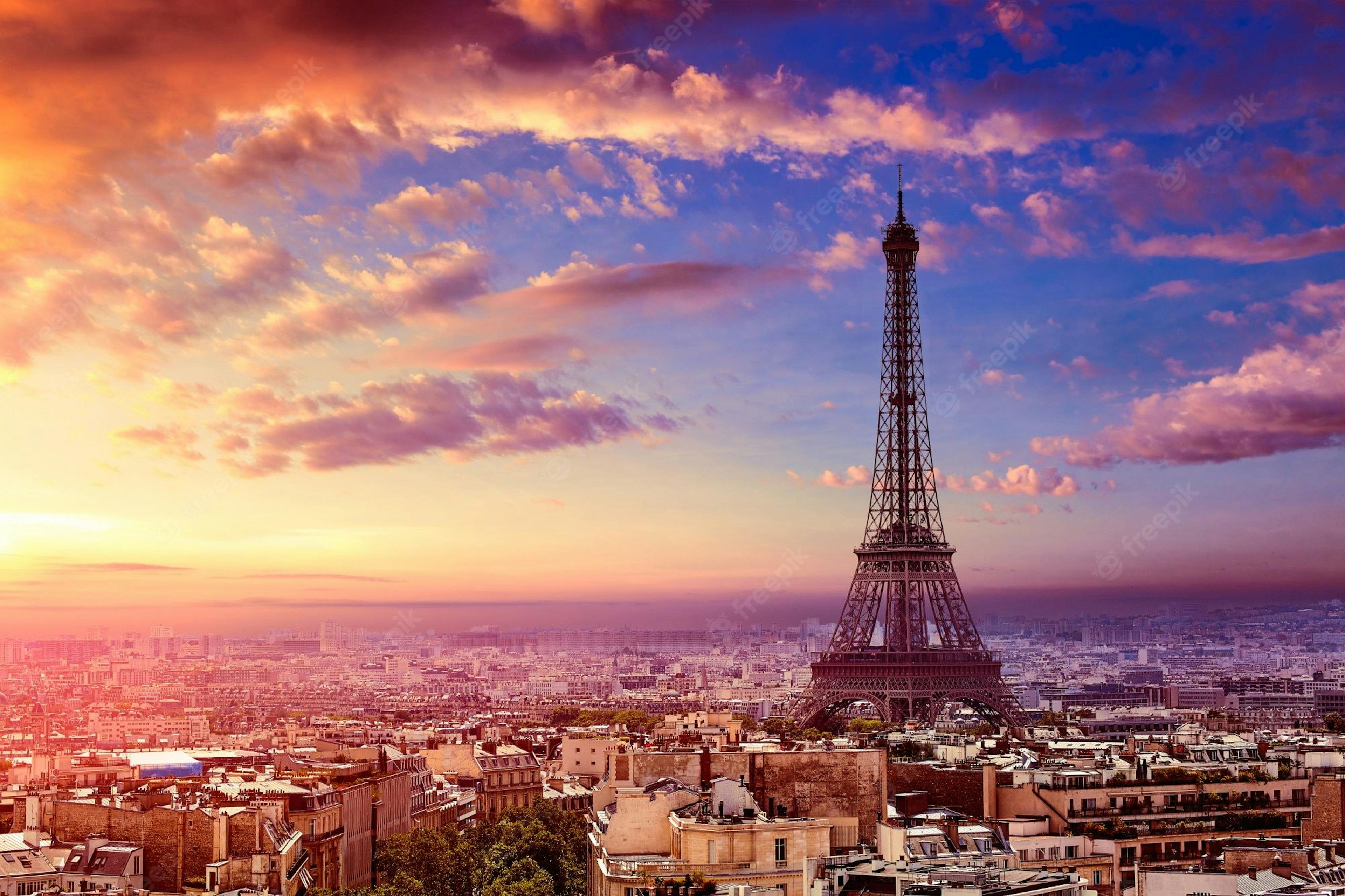 The Eiffel tower surrounded by buildings during sunrise.